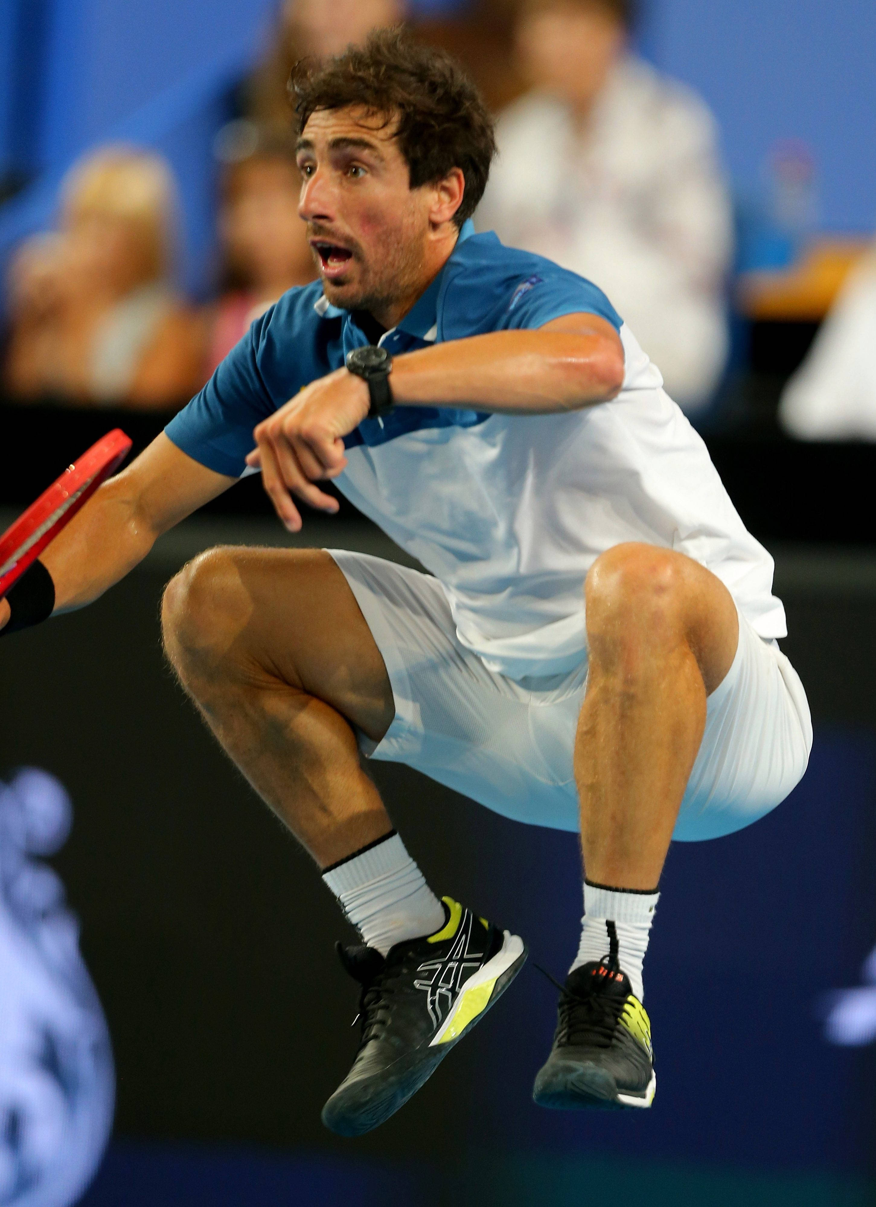 Tennis 桌布 壁紙 — 一名男性網球運動員在空中做出動態弓步，專注地握著球拍，身處藍色球場。