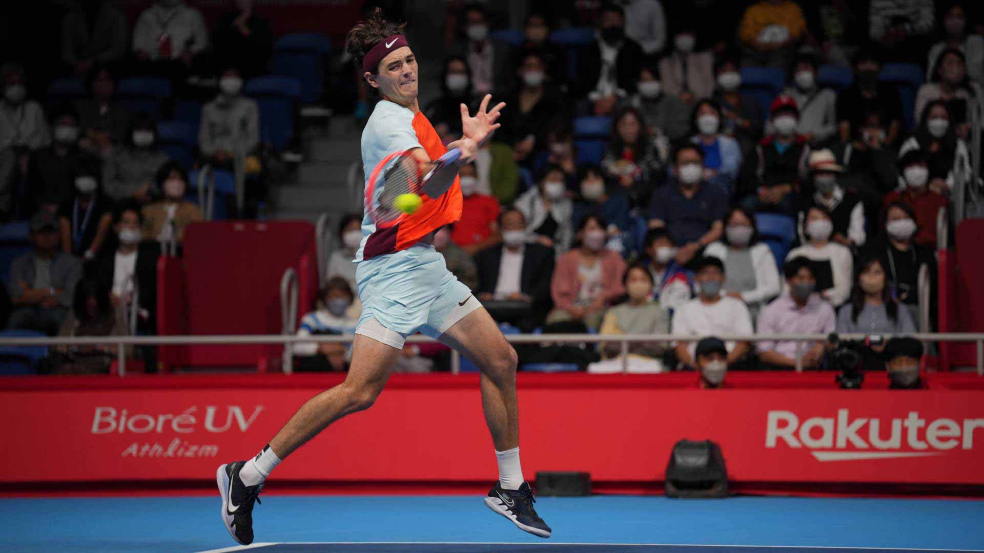 Tennis 桌布 壁紙 — 一名男性網球運動員在藍色球場上揮拍正手擊球，背景有戴著口罩的觀眾。