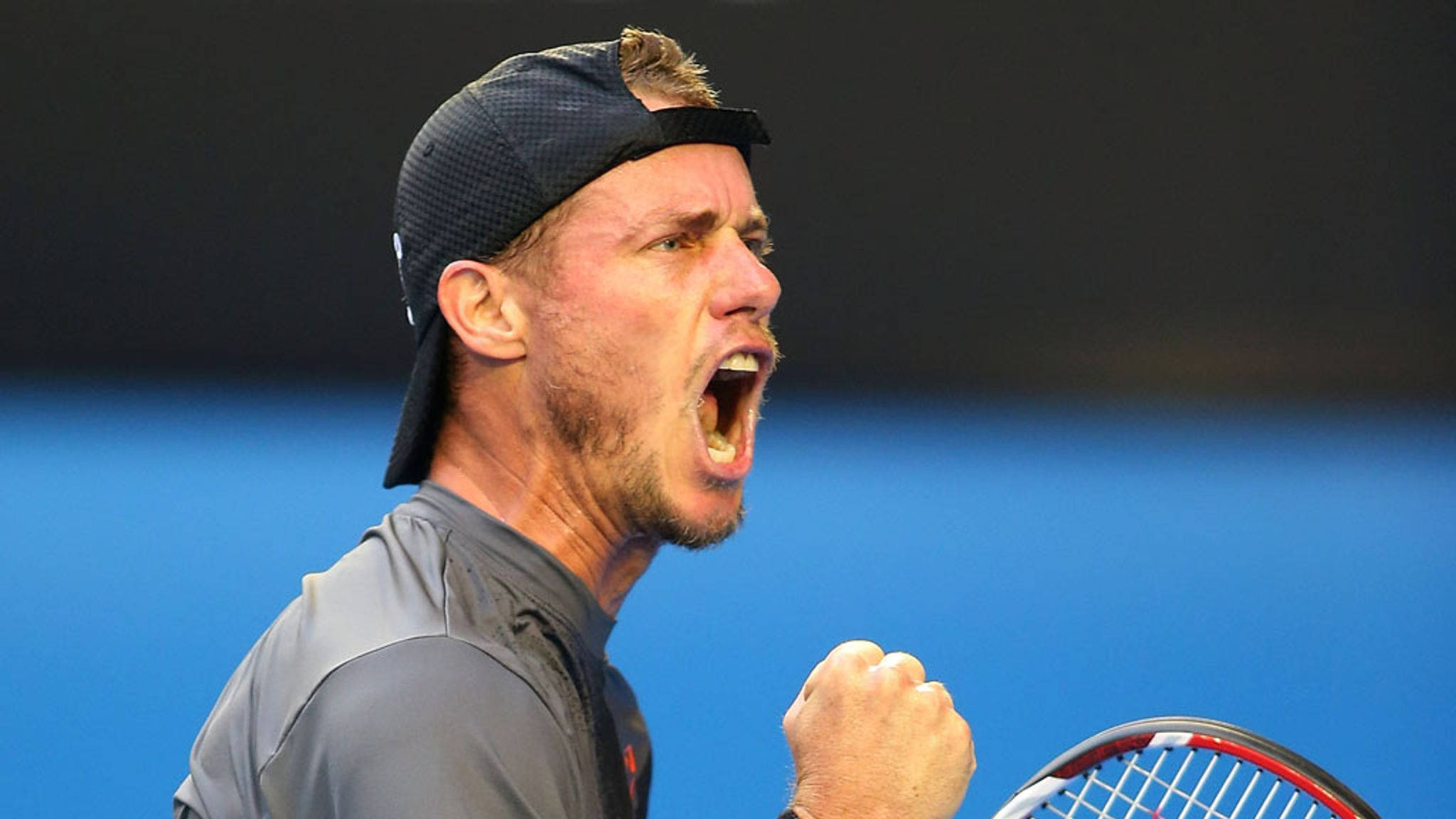 Australian Open 桌布 壁紙 — 一名男性網球運動員在藍色球場背景下握緊拳頭高舉球拍，勝利地吶喊。