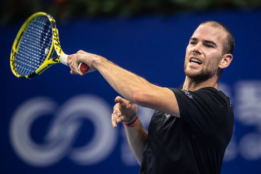 Tennis 桌布 壁紙 — 一名男性網球運動員在藍色球場背景下，專注地揮拍中。
