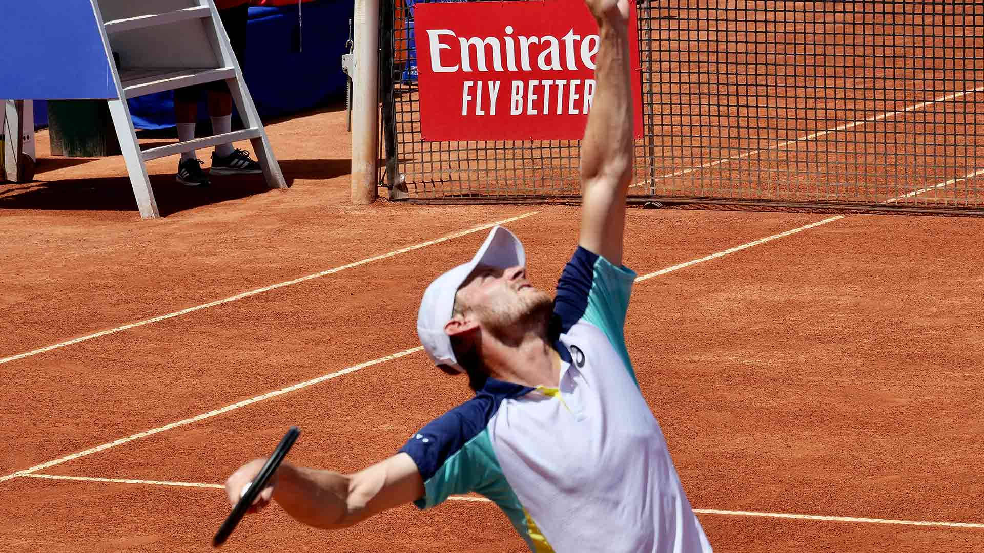 Tennis 桌布 壁紙 — 一名男性網球運動員在陽光明媚的紅土球場上正準備發球，網後可見阿聯酋航空的廣告。