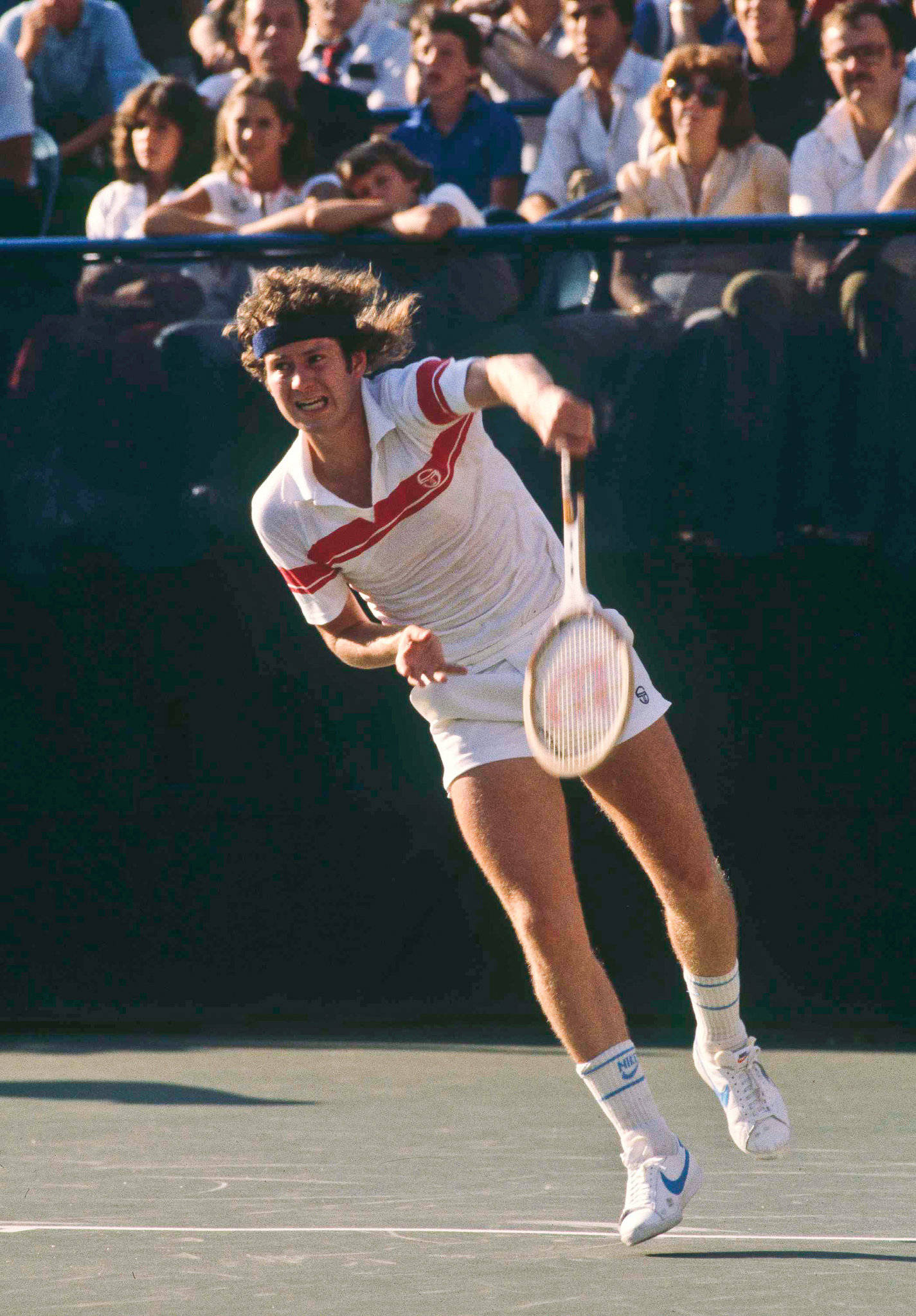 Tennis 桌布 壁紙 — 一名男性網球選手在半空中，於陽光普照的球場上執行強力的正手揮拍，背景有觀眾。