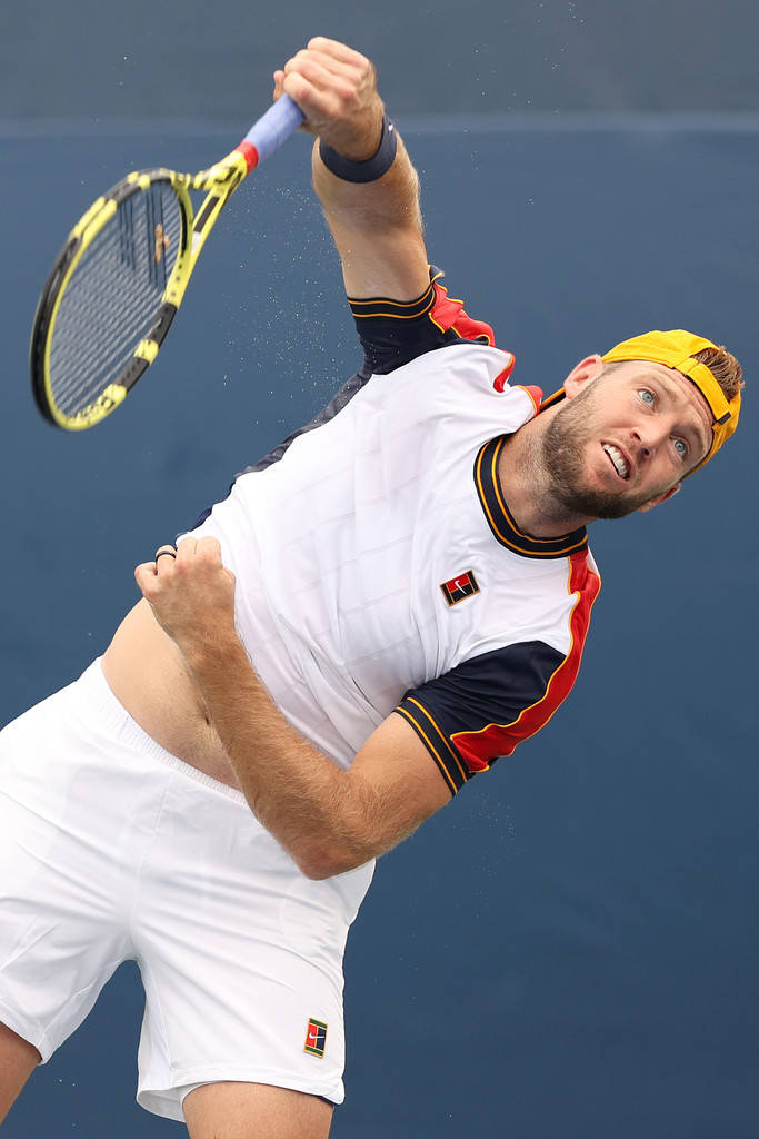Tennis 桌布 壁紙 — 一名男性網球選手在半空中執行強力的過頭扣殺，專注力十足，背景為純藍色球場。