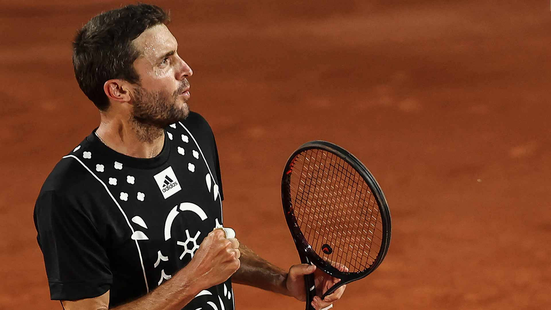 運動 桌布 壁紙 — 一名男性網球選手在球場燈光下於紅土場上握拳慶祝勝利。