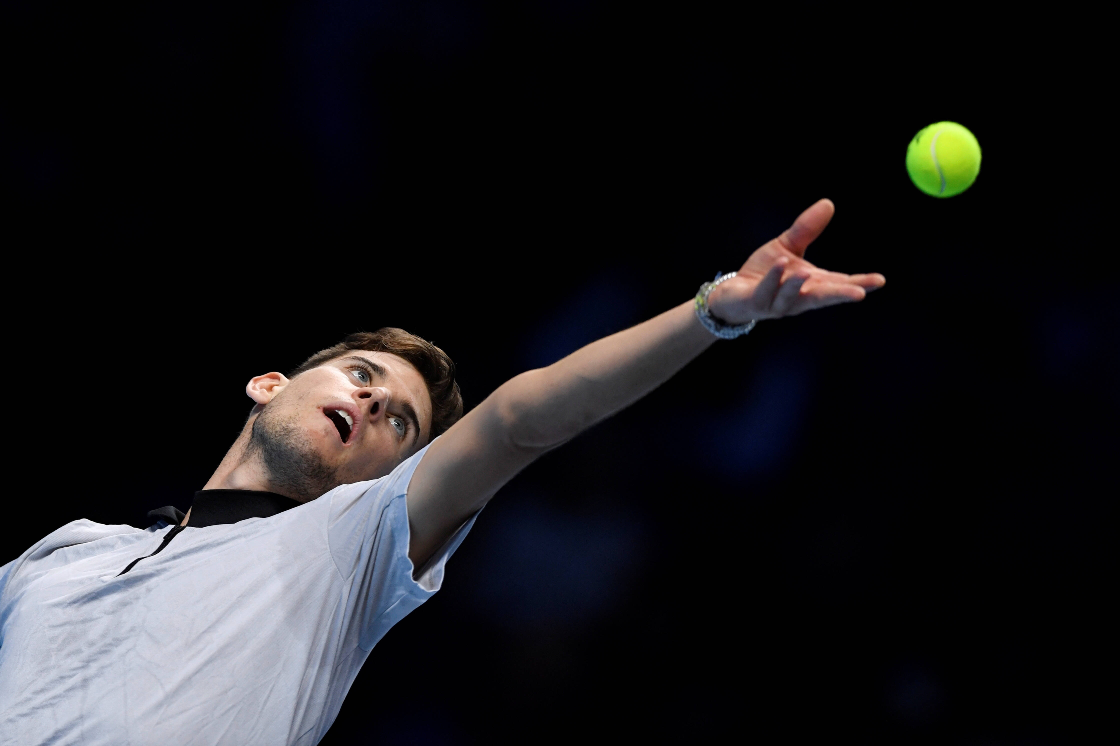 dominic thiem 桌布 壁紙 — 一名男性網球選手在發球中將一顆亮黃綠色的球拋向深色背景。