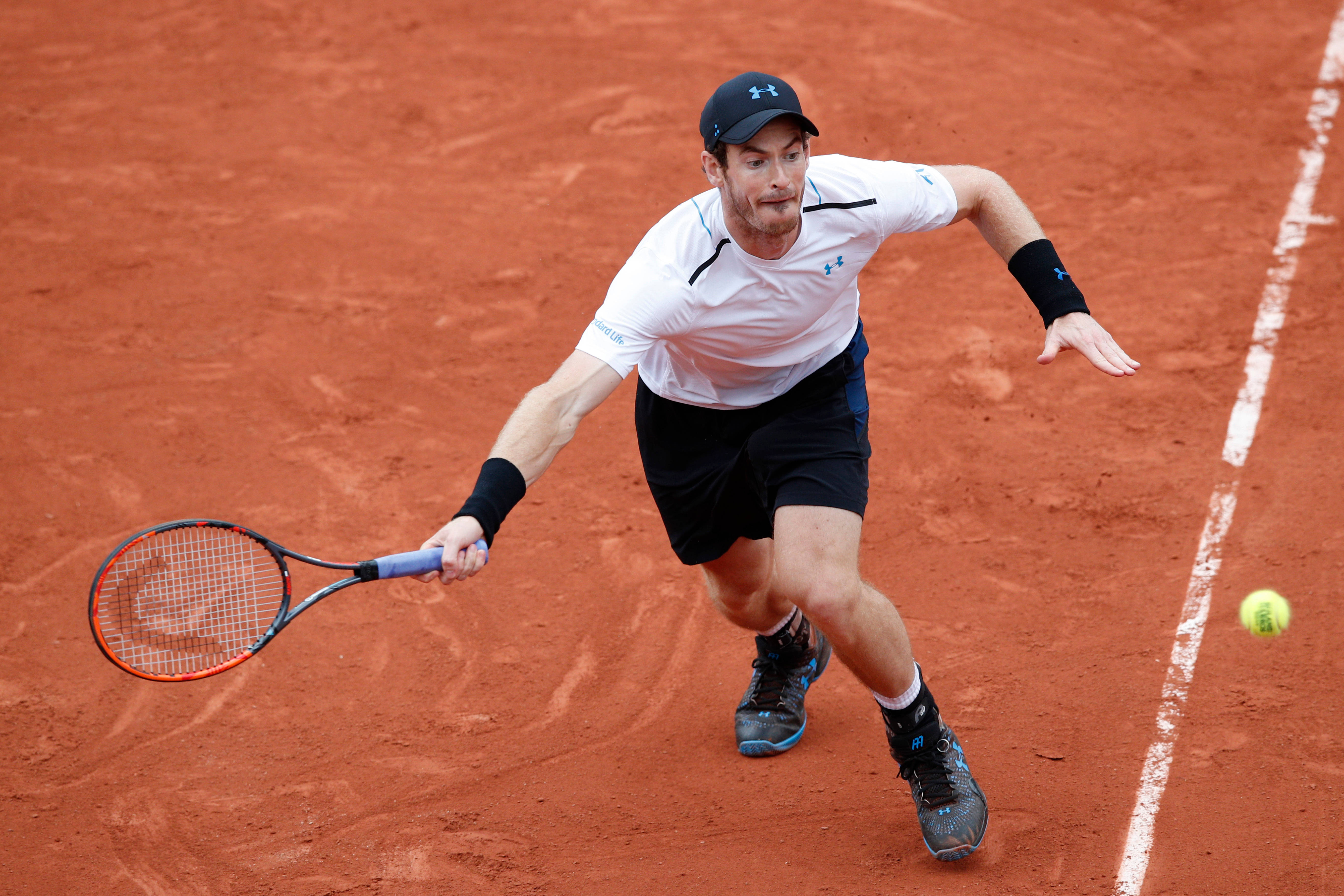 Tennis 桌布 壁紙 — 一名男性網球選手在紅土球場上向前撲出，以高度專注力擊打一個低位的黃色球。