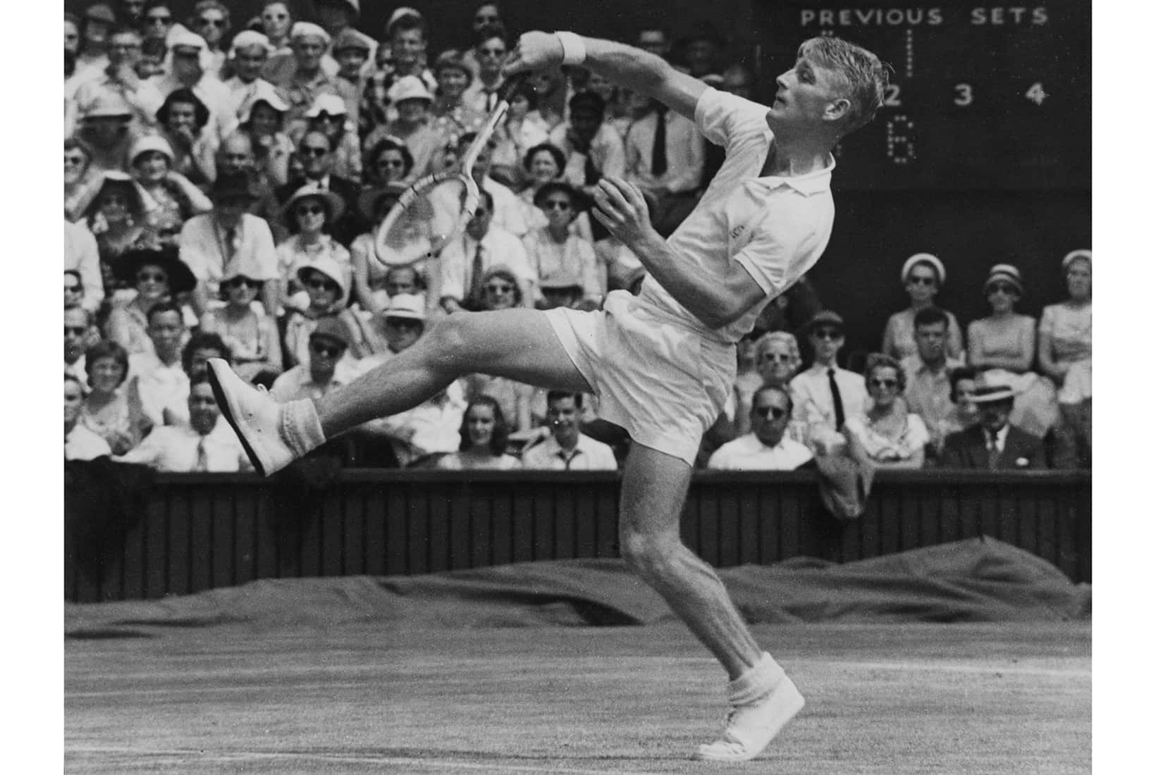 Tennis 桌布 壁紙 — 一名男性網球選手在草地上跳起揮拍，觀眾以黑白畫面觀看。