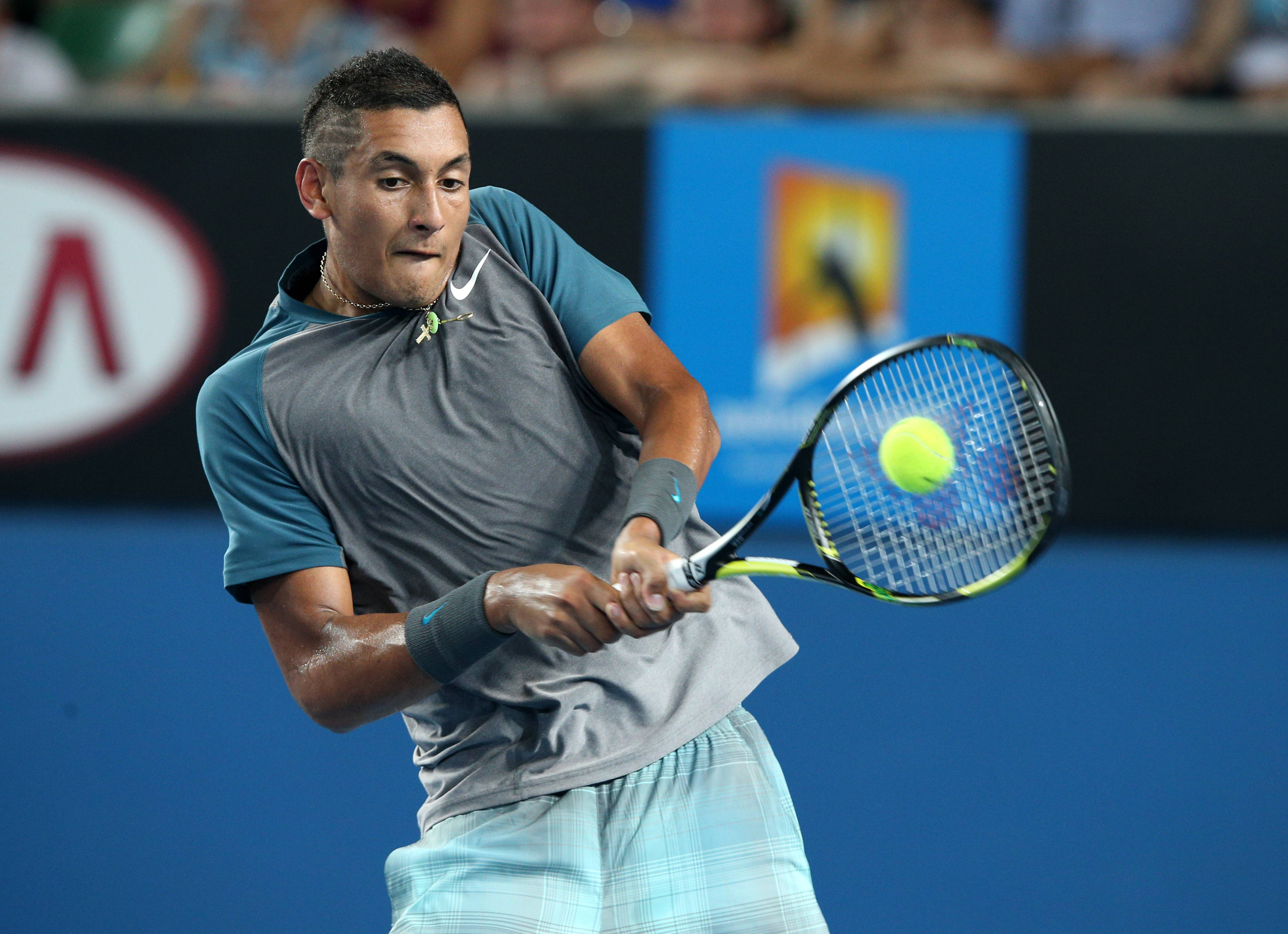 Kyrgios 桌布 壁紙 — 一名男性網球選手在體育場燈光下揮拍擊打亮黃色的球，進行一場激烈的比賽。