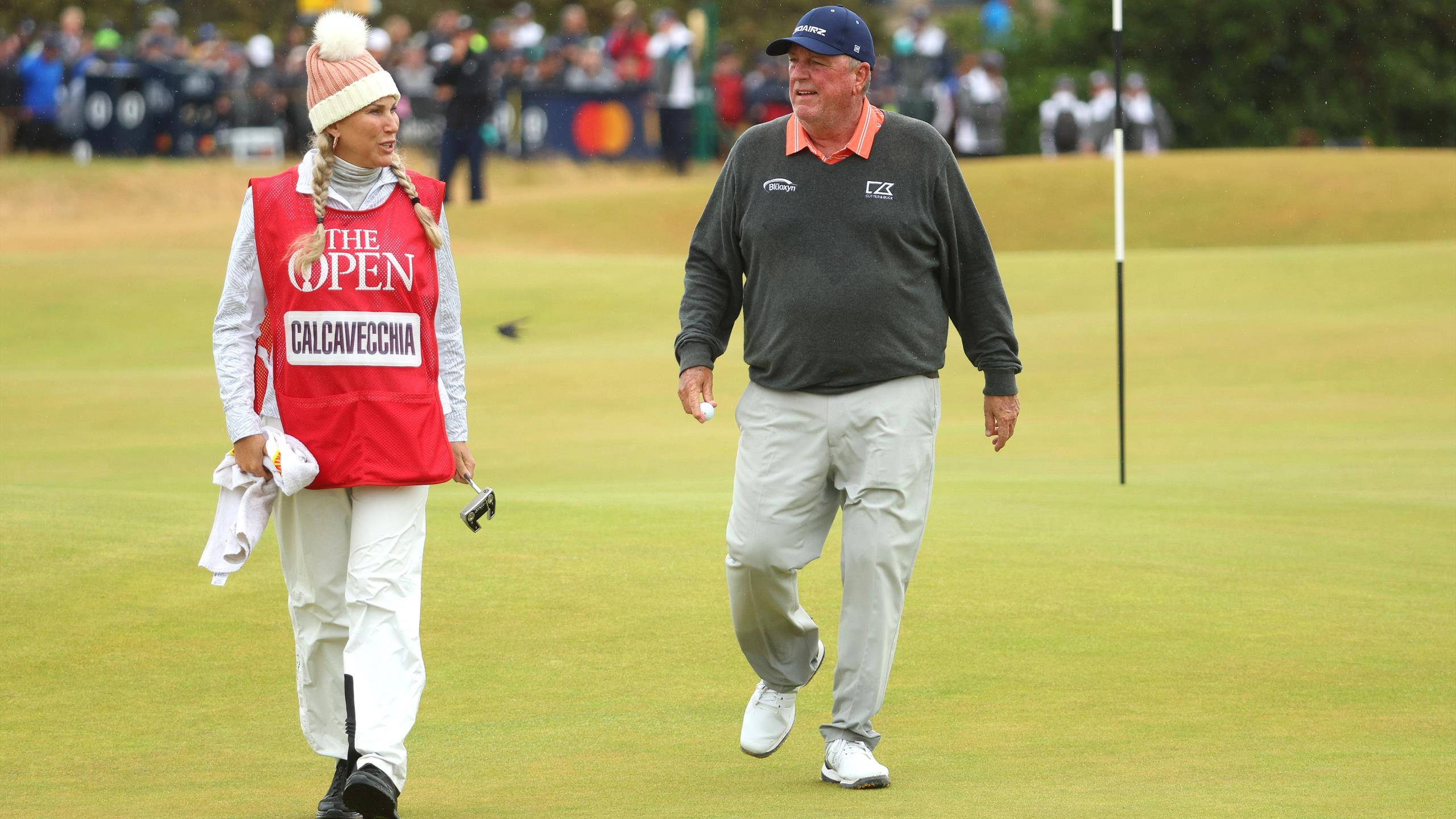 情侶 桌布 壁紙 — 一名男性高爾夫球手和一名女性球童在The Open Championship期間走過鬱鬱蔥蔥的高爾夫球場，背景有觀眾。
