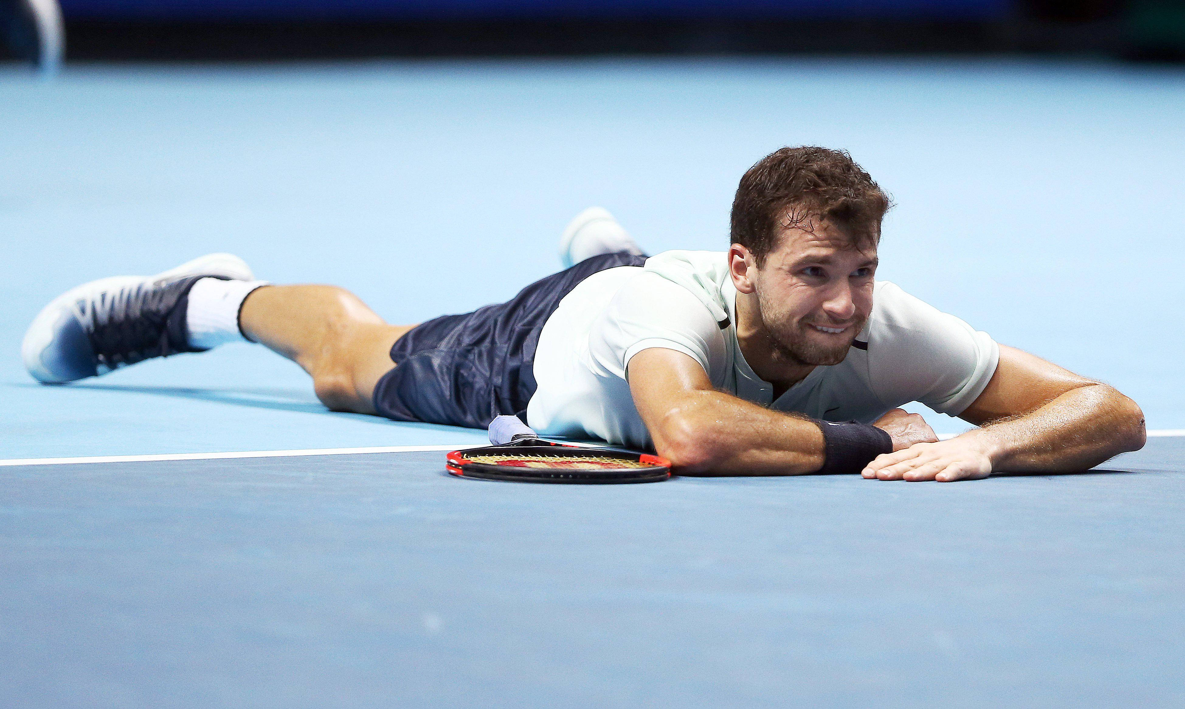 Tennis 桌布 壁紙 — 一名男網球運動員在藍色球場上筋疲力盡地躺著，比賽後微笑，球拍放在身旁。