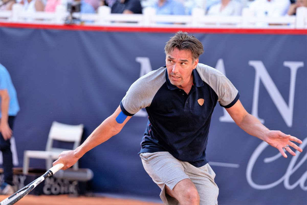 Tennis 桌布 壁紙 — 一名男網球選手在紅土球場上向前猛衝，比賽中緊握球拍，專注力極強。