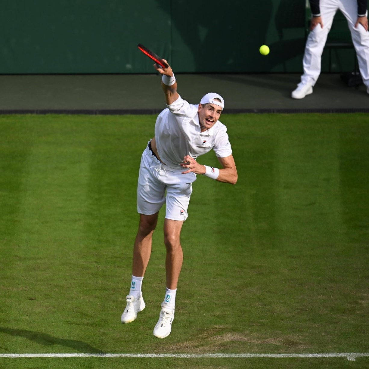 Tennis 桌布 壁紙 — 一名男網球選手在草地場上躍起，以高度專注執行強力發球。