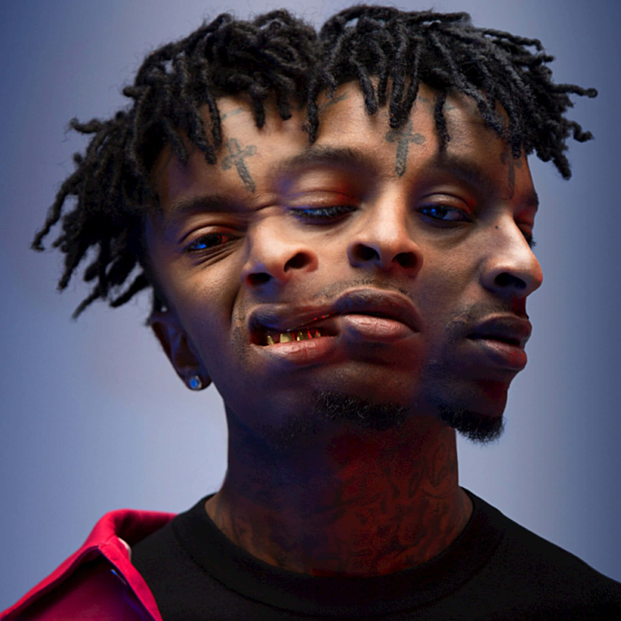 21 Savage 桌布 壁紙 — 一名留有辮子頭和面部刺青的男子在戲劇性的藍色和紅色燈光下的特寫肖像。