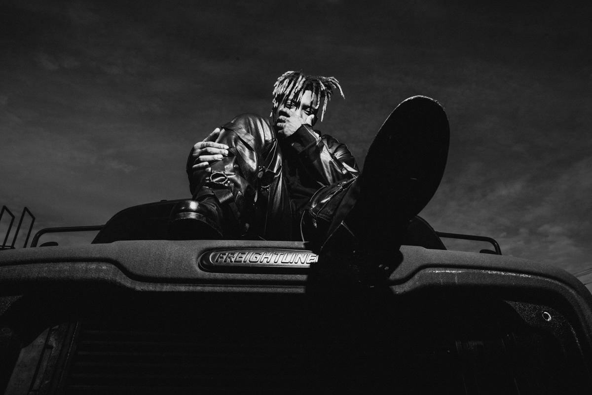 Juice Wrld Desktop 桌布 壁紙 — 一名留著辮子的人坐在 Freightliner 卡車引擎蓋上，在戲劇性的單色燈光下拿著滑板。