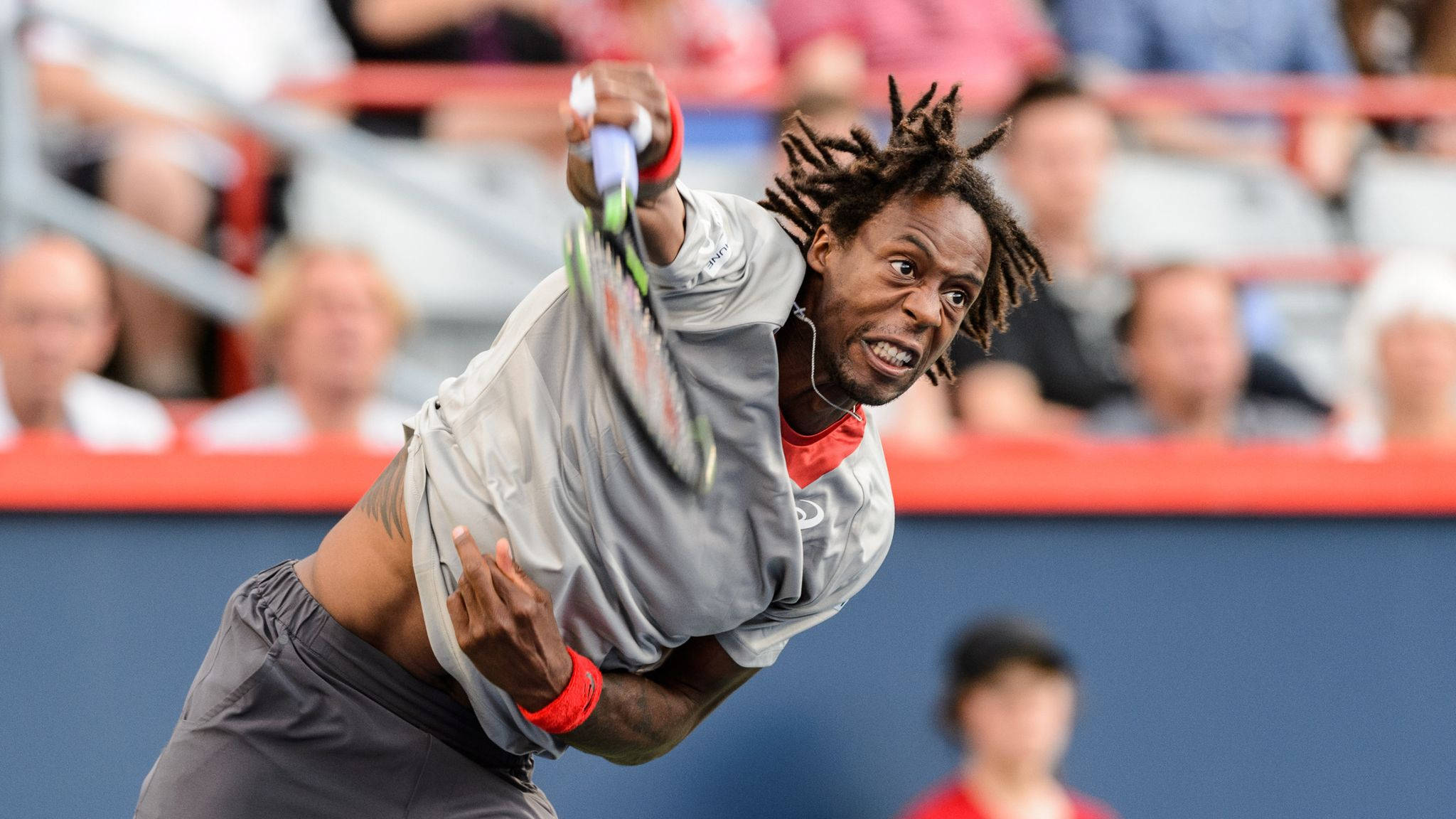Athletic 桌布 壁紙 — 一名留著辮子的男性網球選手在藍色球場上比賽時，專注地揮動球拍。