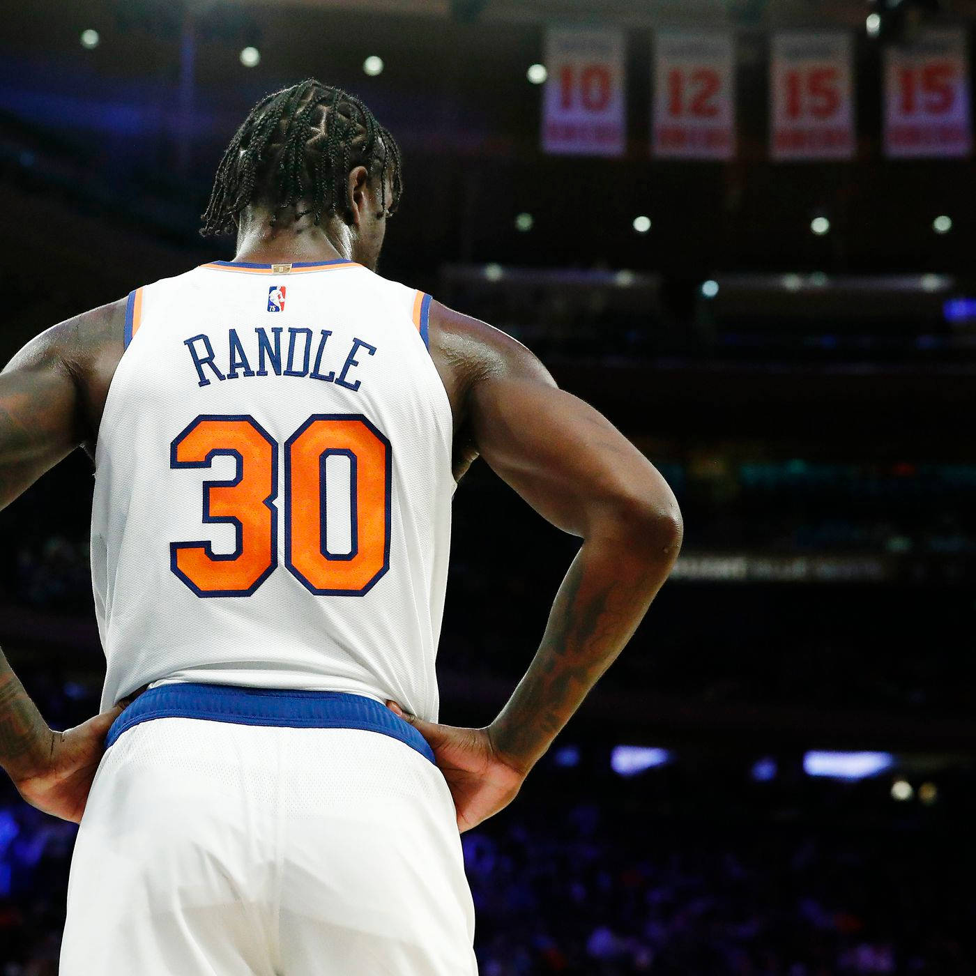 NBA 桌布 壁紙 — 一名留著辮子的籃球運動員，身穿白色球衣，上面有橙色30號，雙手叉腰，背對鏡頭，站在燈光昏暗的球場上。