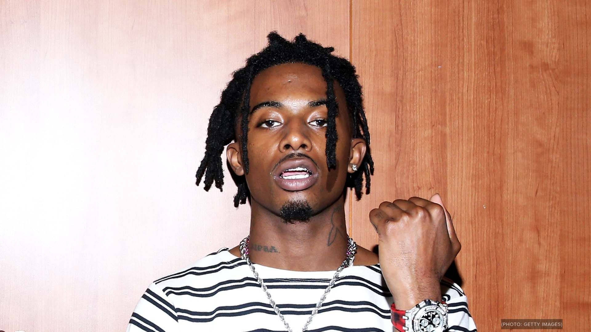 Carti 桌布 壁紙 — 一名留著辮子頭、身穿條紋襯衫的男子，戴著手錶和鏈條，自信地靠著木牆擺姿勢。