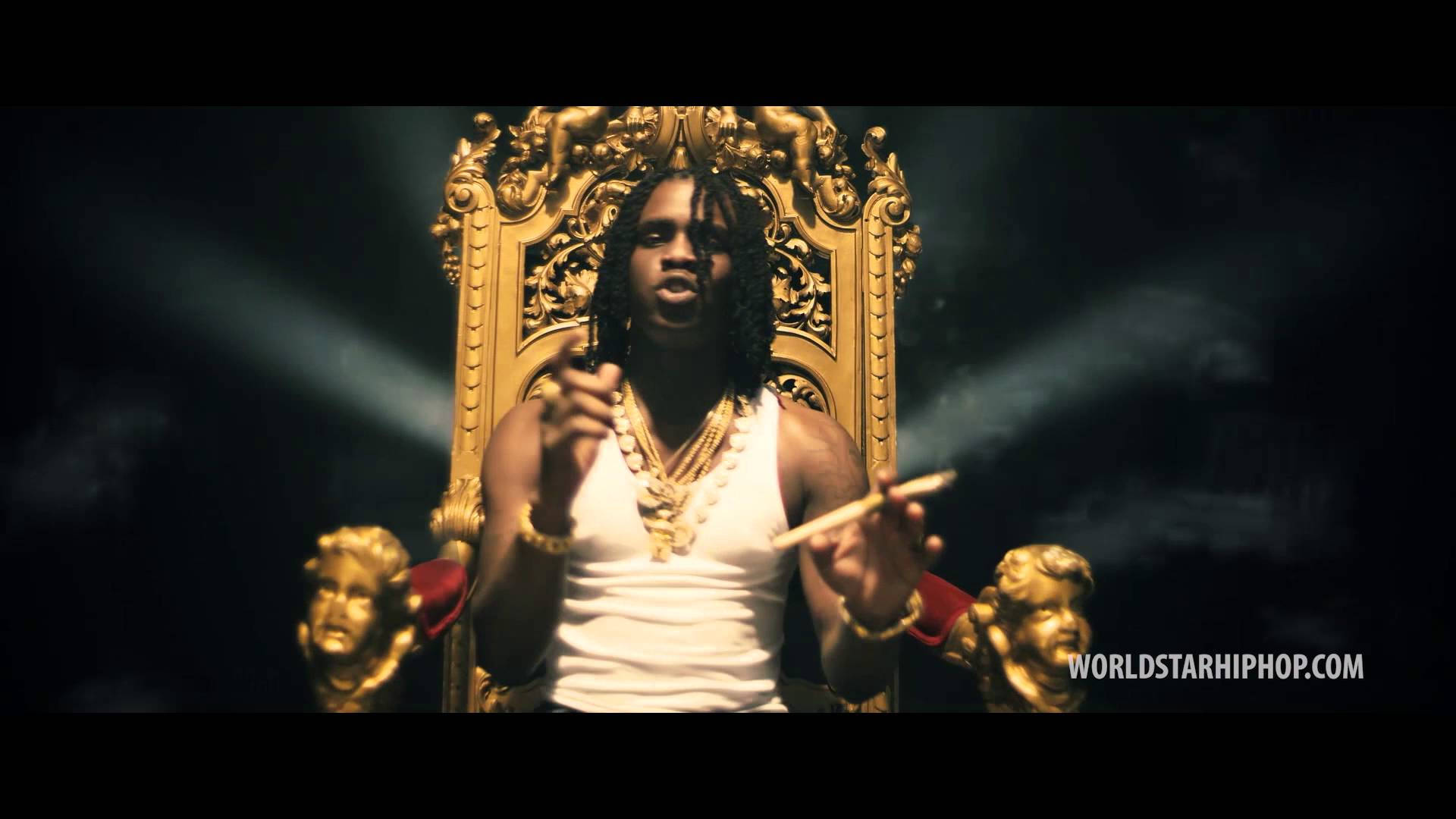 Chief Keef 桌布 壁紙 — 一名留著辮子頭的男人，在黑暗戲劇性的場景中，威嚴地坐在華麗的金色王座上，手持雪茄。