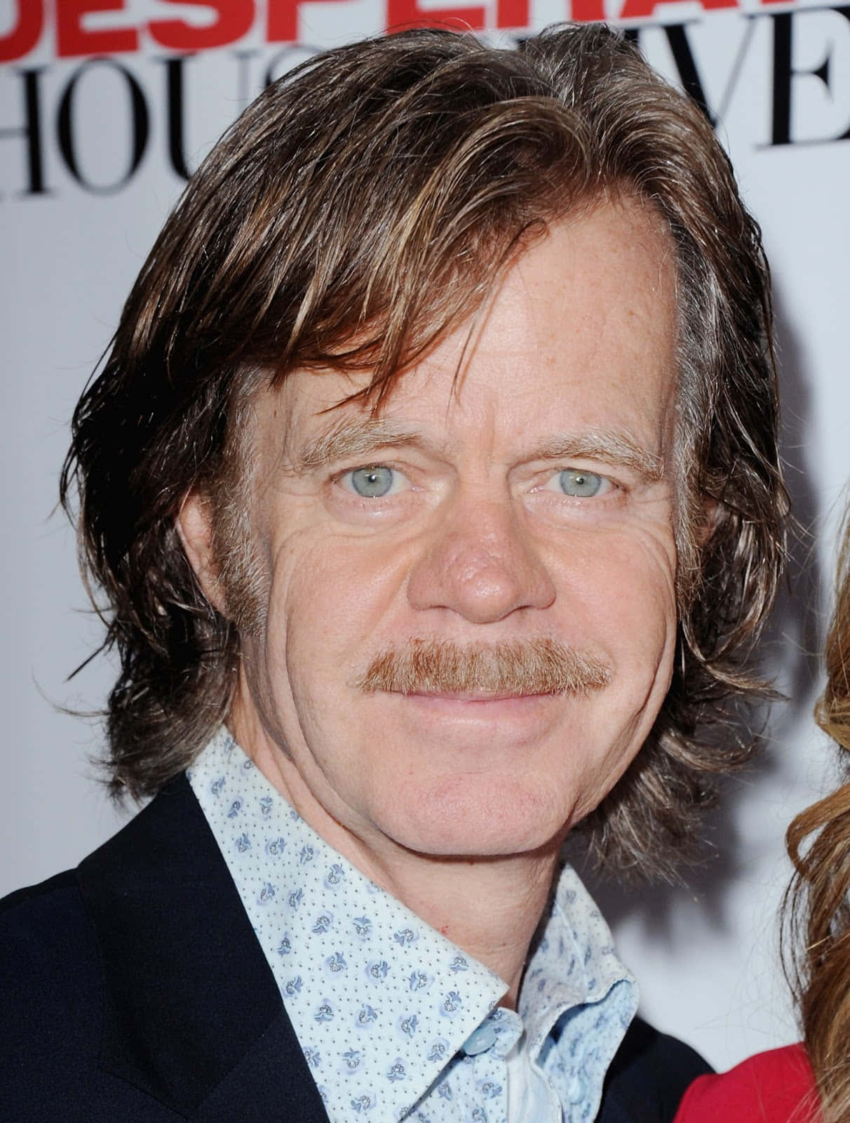 william h. macy 桌布 壁紙 — 一名留著長棕髮和鬍鬚的男士特寫肖像，穿著圖案襯衫和深色外套。