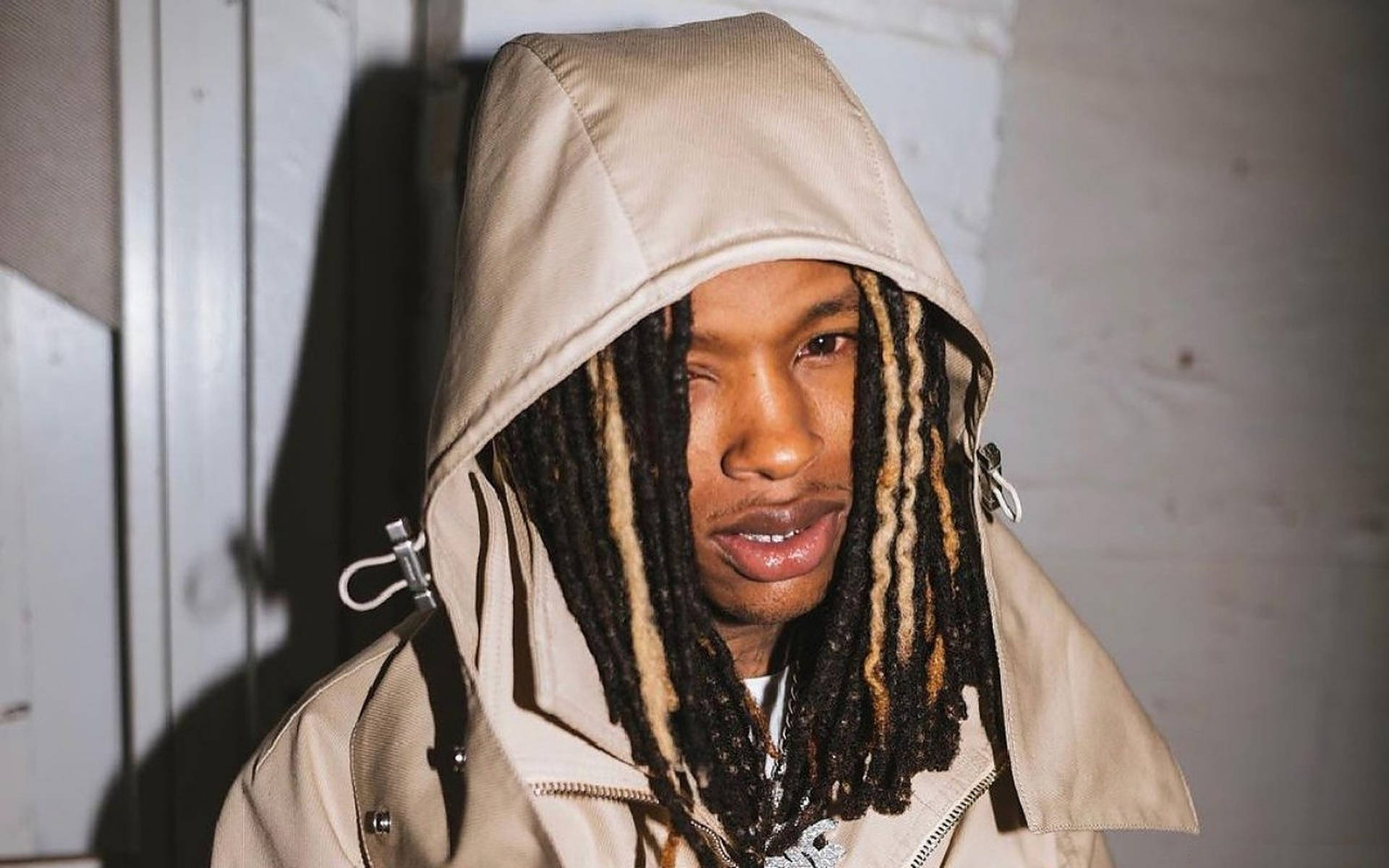 身穿米色連帽衫、留著長辮子的男子室內站立。 — King Von 壁紙