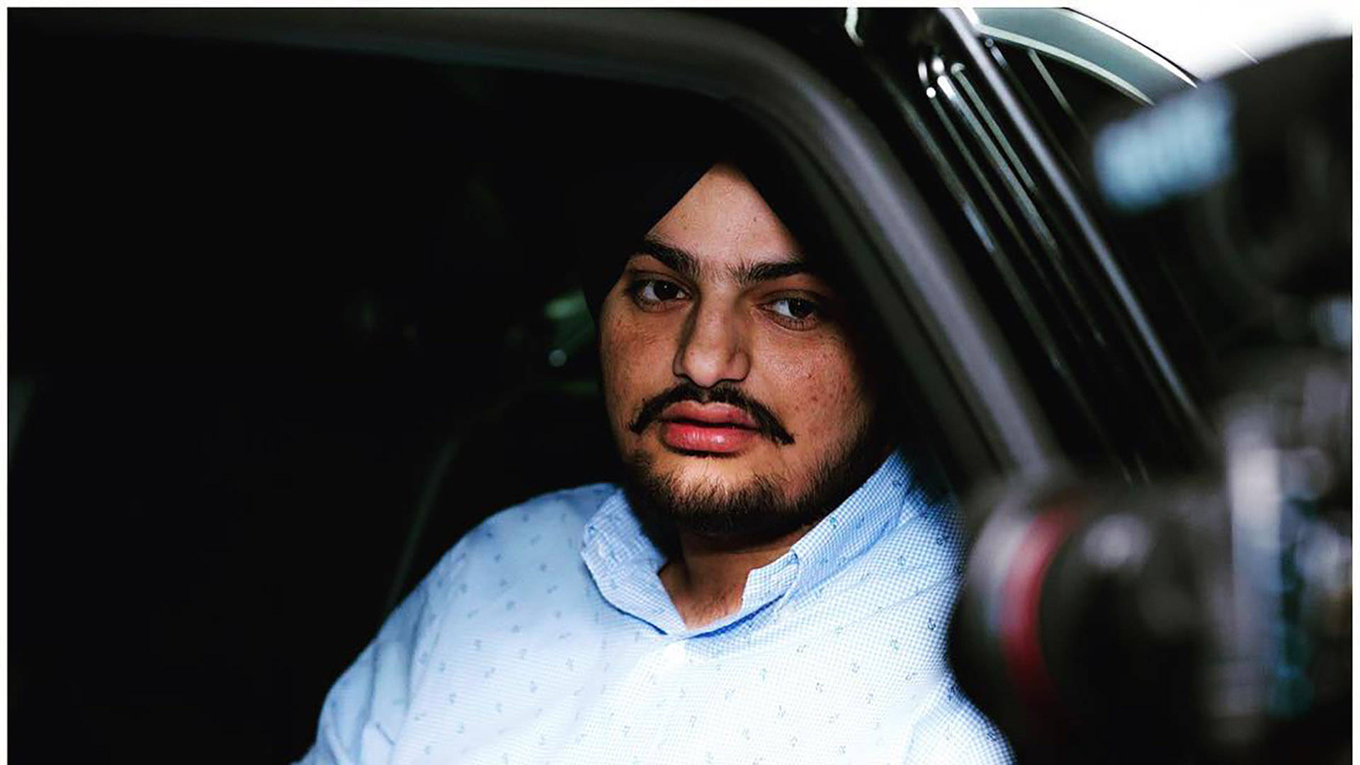 留鬍子戴頭巾的男子坐在車內看著相機 — Sidhu Moose Wala 壁紙