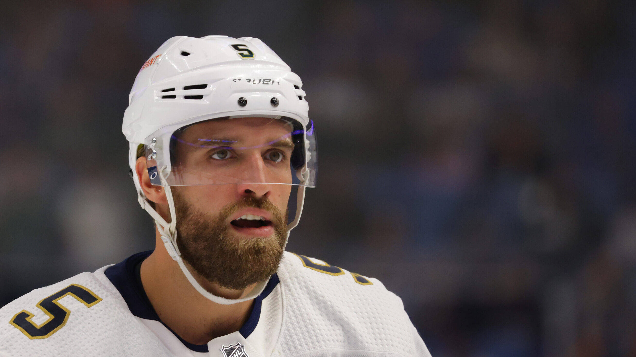 hockey 桌布 壁紙 — 一名留鬍鬚的冰球運動員身穿白色裝備，背號5，比賽中表情專注的近距離特寫。