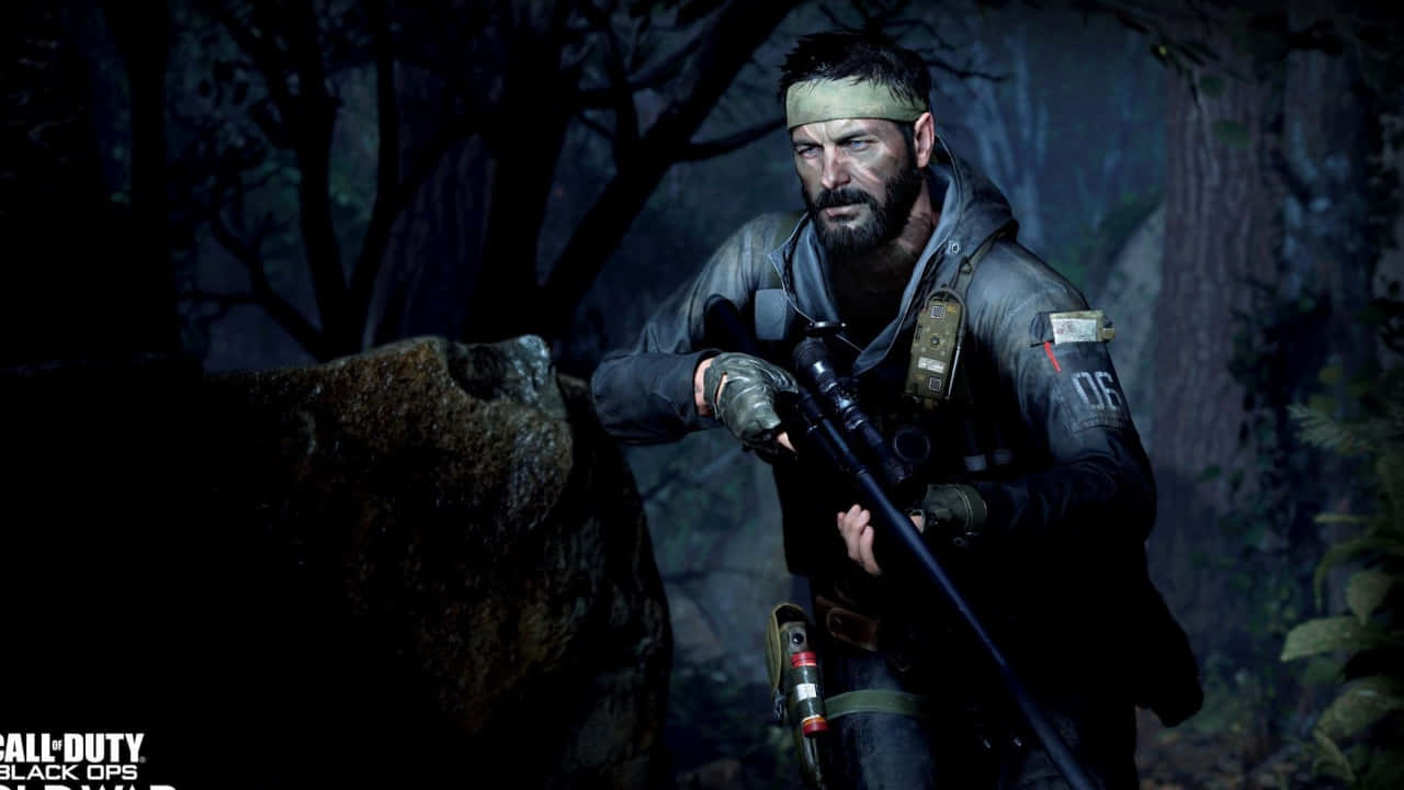 720p Call Of Duty Black Ops Cold War 桌布 壁紙 — 一名留鬍鬚的士兵身穿戰術裝備，在黑暗霧濛濛的森林中蹲在岩石後面，手持狙擊步槍。