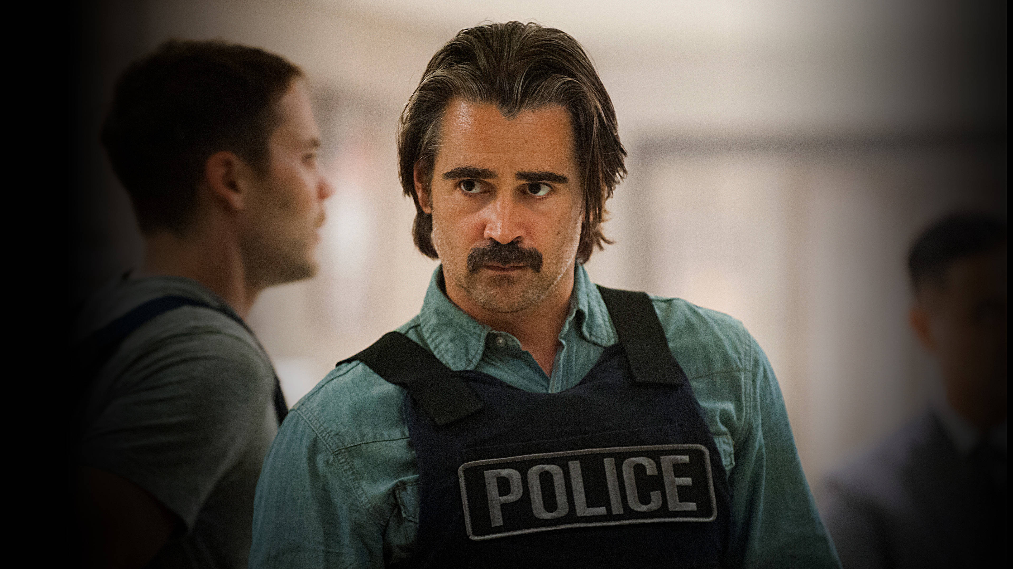 true detective 桌布 壁紙 — 一名留鬍鬚的男子在昏暗的室內環境中，穿著一件警察背心，內搭青綠色襯衫，並專注地凝視著鏡頭。