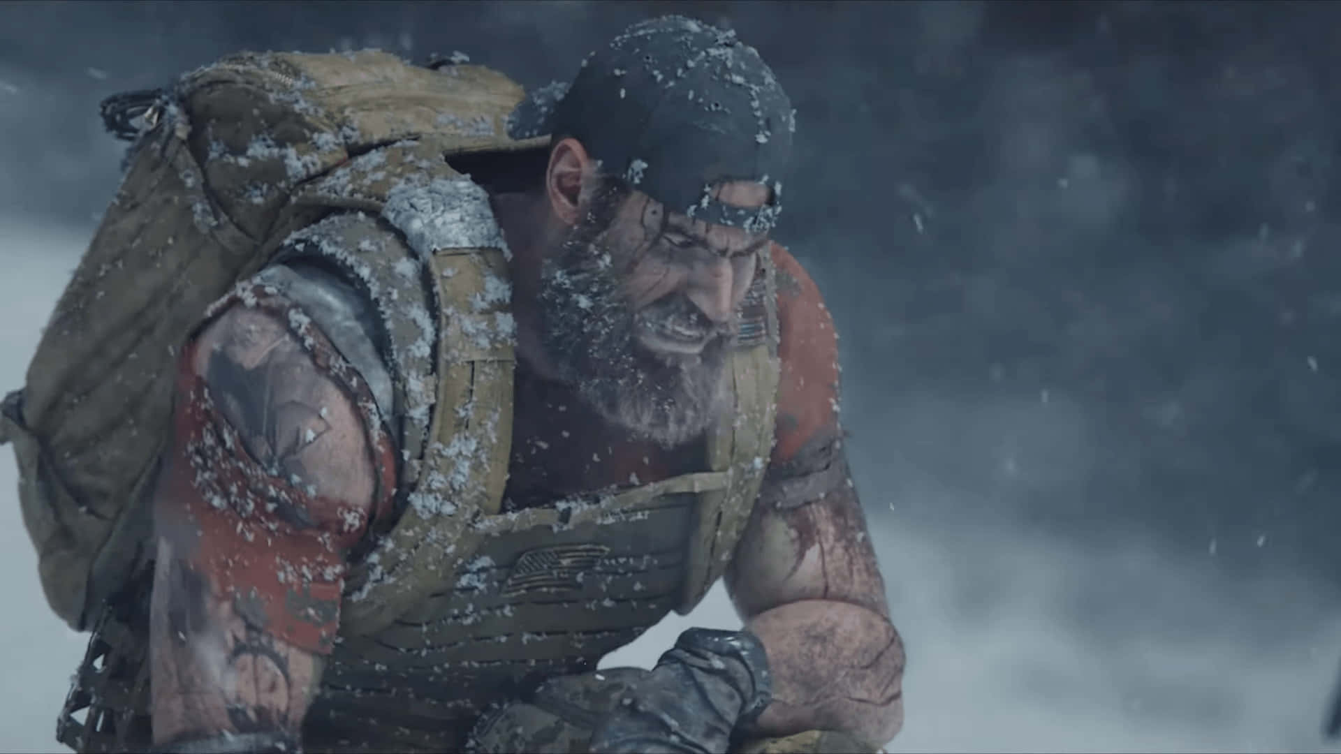 Ghost Recon 桌布 壁紙 — 一名留鬍鬚的粗獷士兵身穿戰術裝備，在暴風雪中奮戰，雪花附著在他的盔甲和臉上。