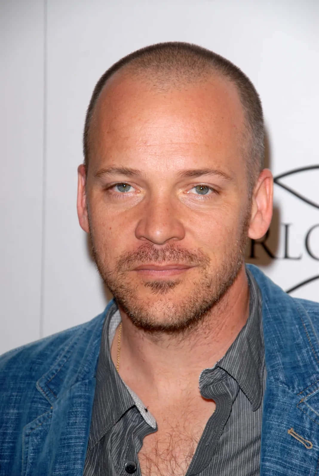Peter Sarsgaard 桌布 壁紙 — 一名短髮、鬍渣的男子穿著牛仔外套搭配條紋襯衫的特寫肖像。