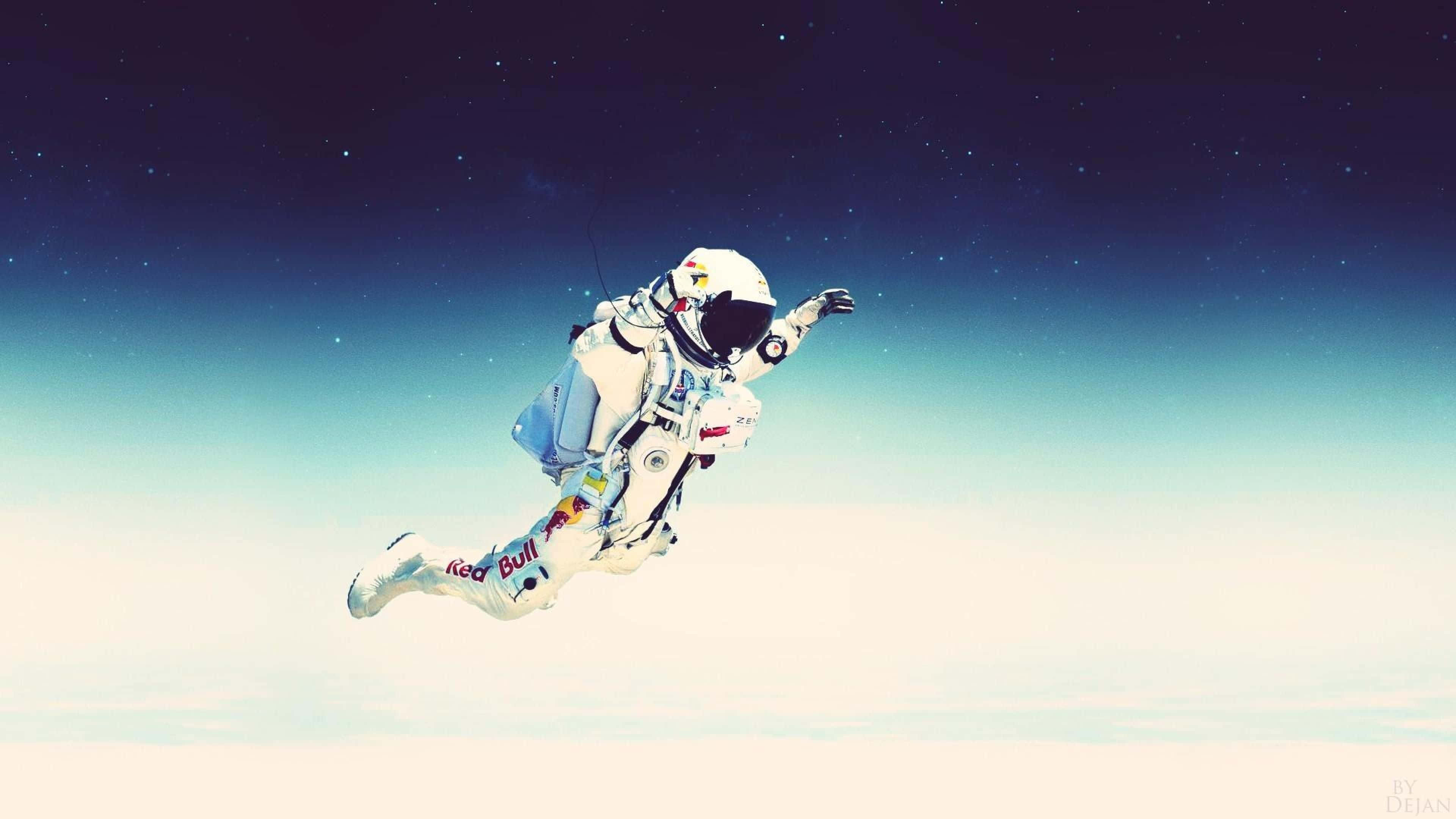 Astronaut Desktop 桌布 壁紙 — 一名穿著Red Bull太空衣的太空人，在繁星點點的夜空背景下，無重狀態地漂浮在地球的雲層之上。