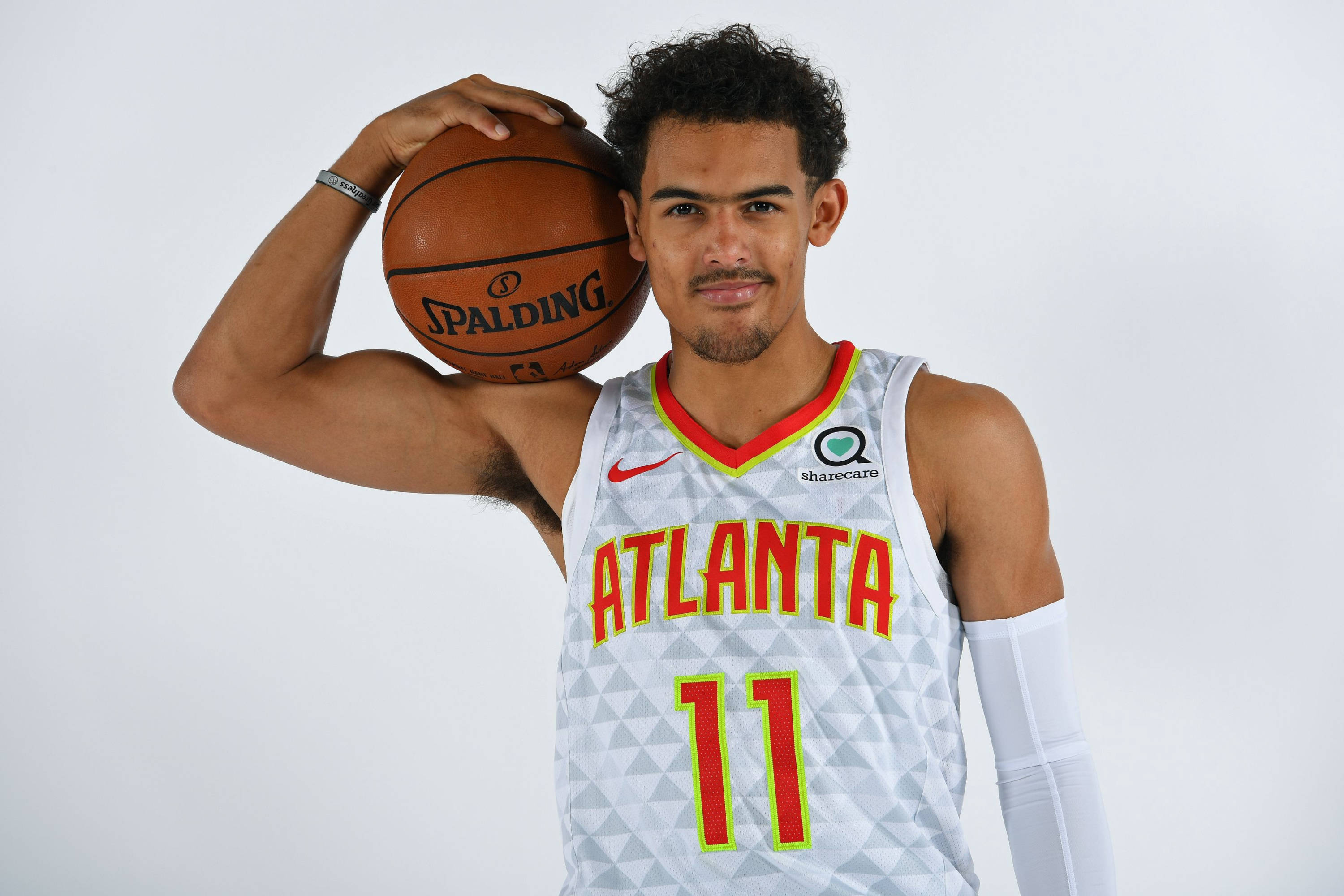 Hawks 桌布 壁紙 — 一名穿著亞特蘭大球衣的籃球運動員在純白色背景前拿著一個Spalding籃球。