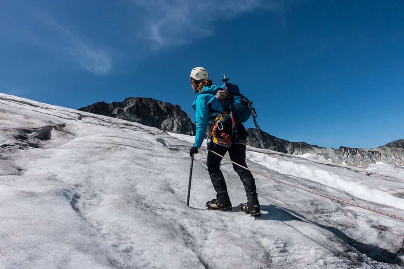 Climbing 桌布 壁紙 — 一名穿著亮藍色外套的登山者，在晴朗的藍天下，用冰斧和繩索攀登陽光照耀的冰川。