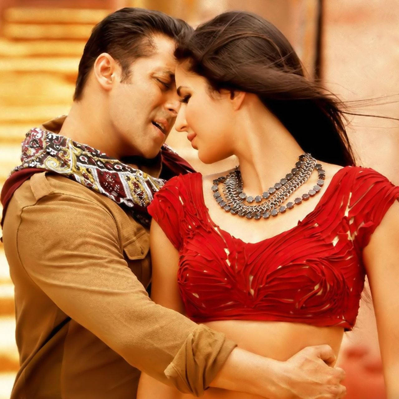 salman khan HD 桌布 壁紙 — 一名穿著傳統服飾的男女，在溫暖的金色背景下額頭相觸，分享親密時刻。