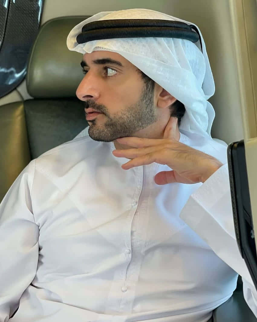 Arab 桌布 壁紙 — 一名穿著傳統白色坎杜拉和古特拉的男人坐在豪華汽車座椅上，手放在脖子上，若有所思地看向一旁。