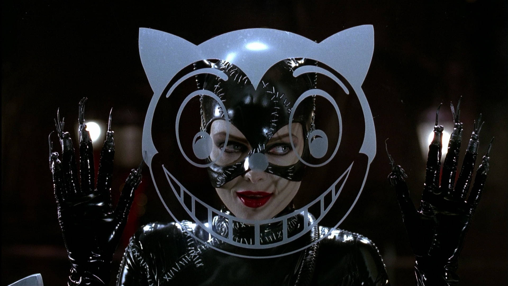 Catwoman 桌布 壁紙 — 一名穿著光澤黑色貓咪服裝、擁有鋒利爪子和紅唇的女性，透過風格化的白色貓咪剪影在黑暗背景中凝視。