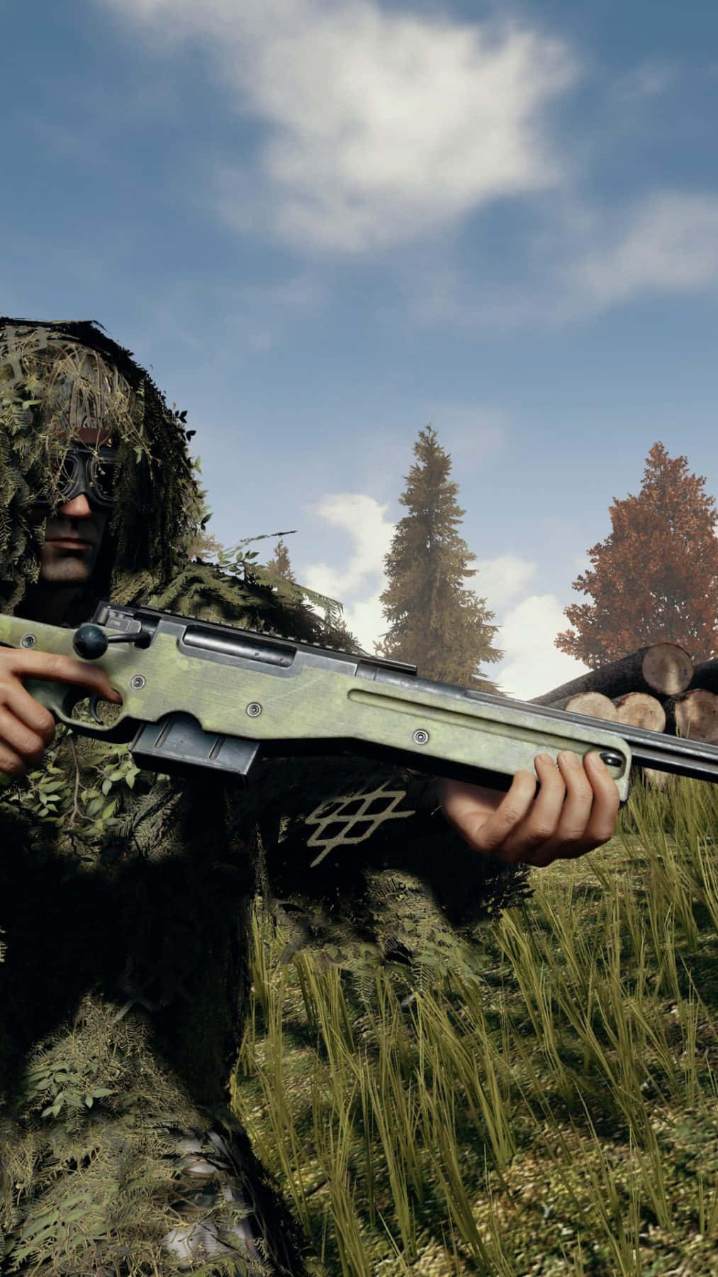 pubg mobile 桌布 壁紙 — 一名穿著全套吉利服的狙擊手，在部分多雲的天空下，從高草叢中瞄準步槍，背景是秋天的樹木。