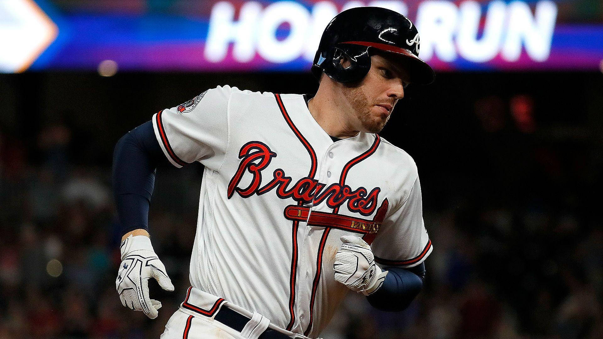 Freddie Freeman 桌布 壁紙 — 一名穿著勇士隊球衣的棒球選手在球場燈光下衝過發光的全壘打標誌。
