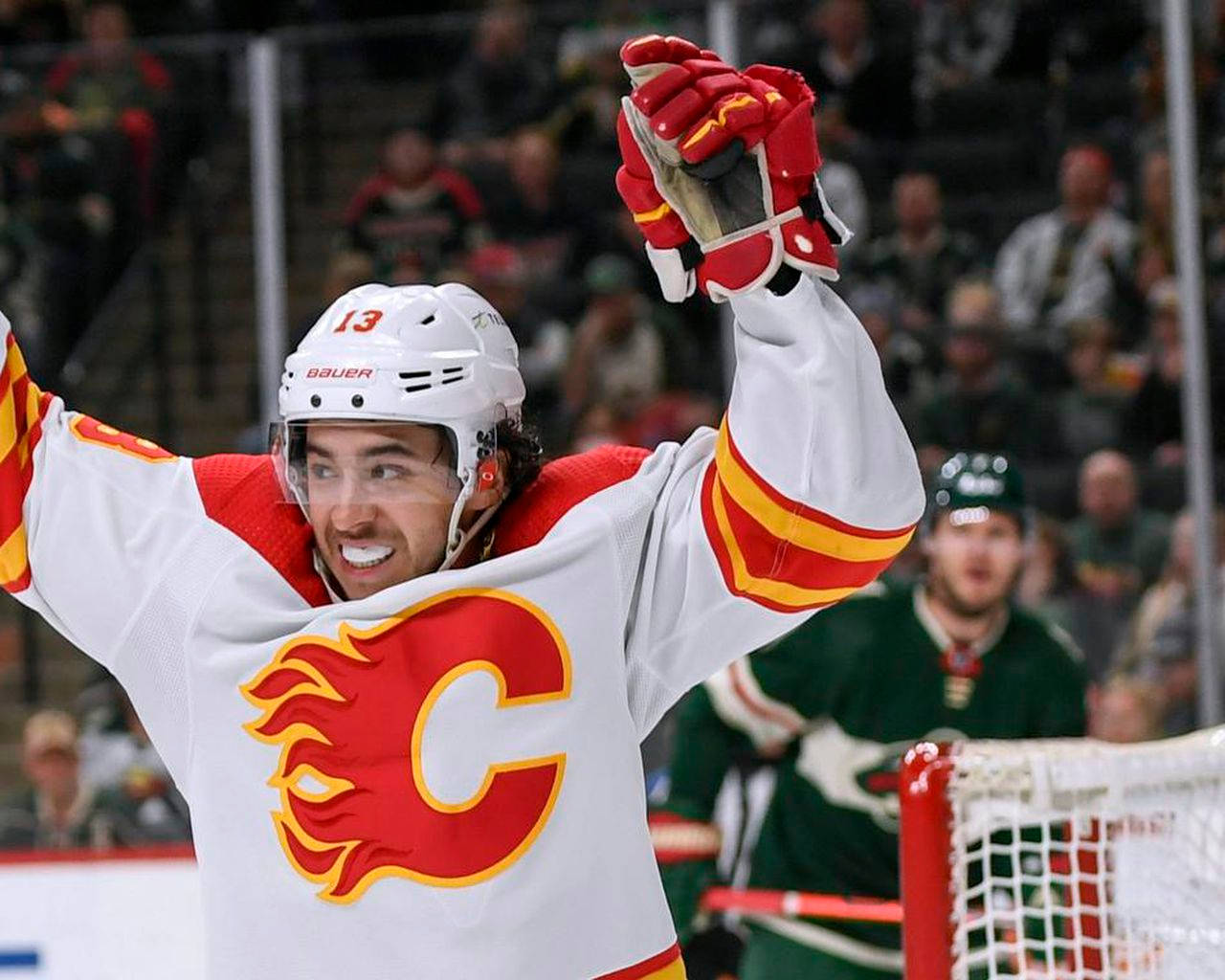 Johnny Gaudreau 桌布 壁紙 — 一名穿著卡加利火焰隊球衣的冰球運動員在冰上高舉雙臂慶祝勝利。