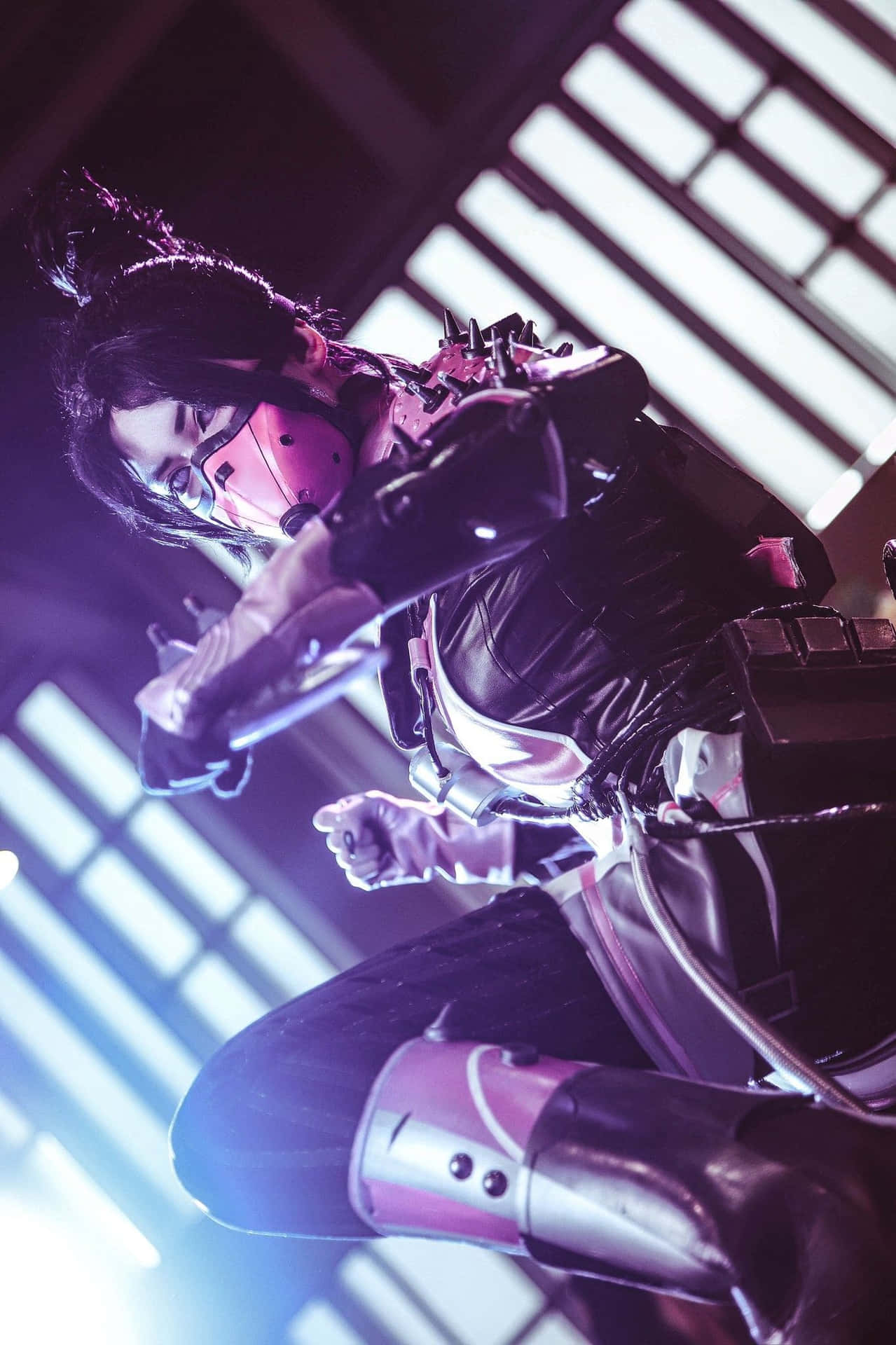 Apex Wraith 桌布 壁紙 — 一名穿著帶有粉紅色點綴的未來風格裝甲服的 Cosplayer，在霓虹燈照亮的百葉窗下動態地蹲伏。