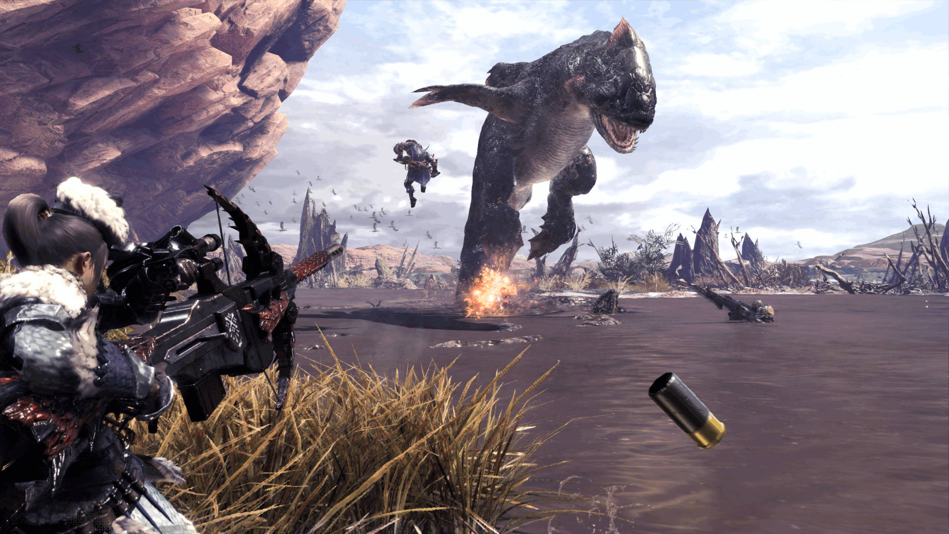 Monster Hunter 桌布 壁紙 — 一名穿著毛皮襯裡盔甲的獵人，在荒涼的岩石荒地中，用弓瞄準一隻巨大的咆哮怪物，前景中有一顆子彈殼飛過。
