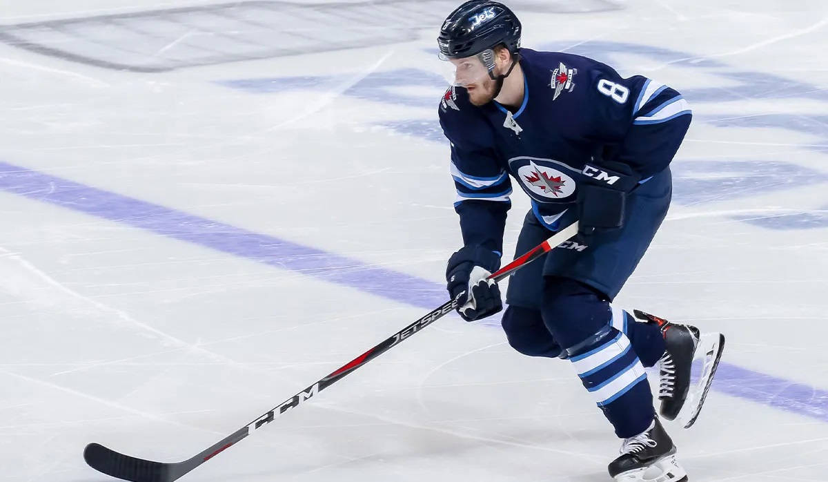 hockey 桌布 壁紙 — 一名穿著溫尼伯噴射機隊球衣的冰球運動員，帶著專注的決心在冰上激烈滑行。