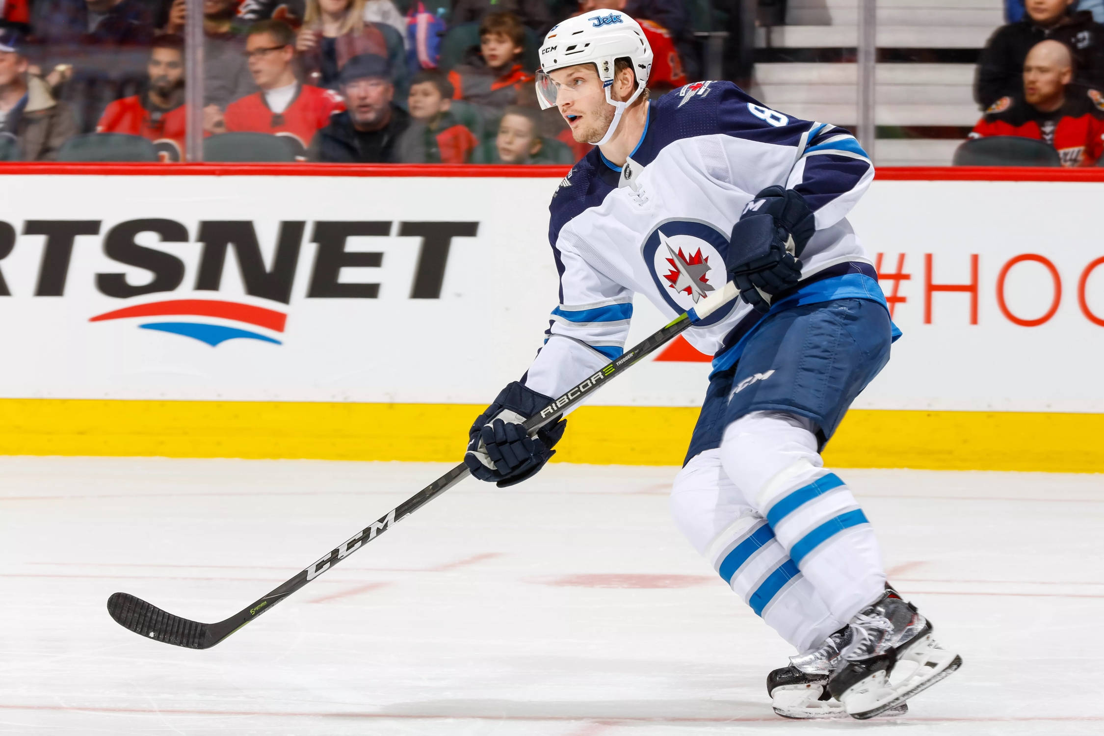 hockey 桌布 壁紙 — 一名穿著溫尼伯噴射機隊球衣的冰球運動員在比賽中專注地、充滿決心地在冰上激烈滑行。