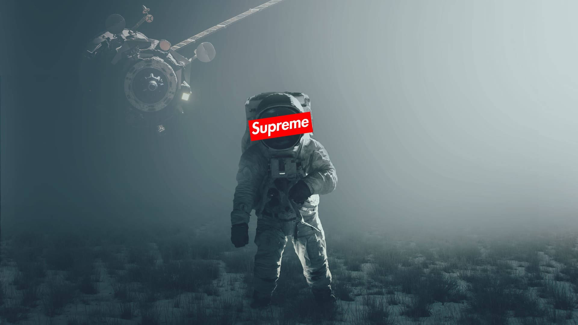 Cool Supreme 桌布 壁紙 — 一名穿著灰色太空衣的太空人站在霧氣瀰漫的外星景觀上，頭頂有衛星盤旋，頭盔上帶有紅色Supreme標誌。