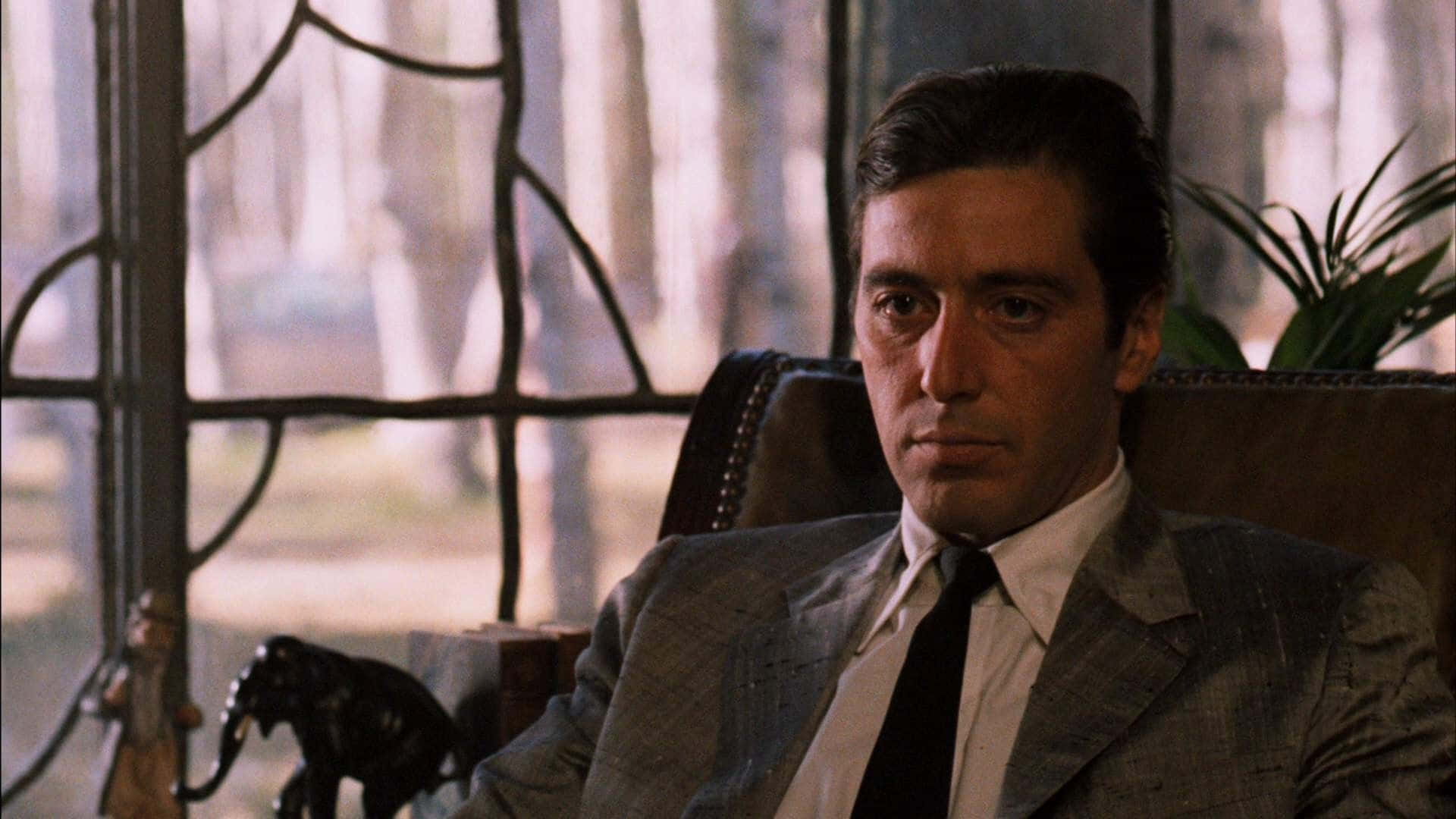 The Godfather 桌布 壁紙 — 一名穿著灰色西裝的男人坐在椅子上，旁邊是帶有森林景色的彩繪玻璃窗。