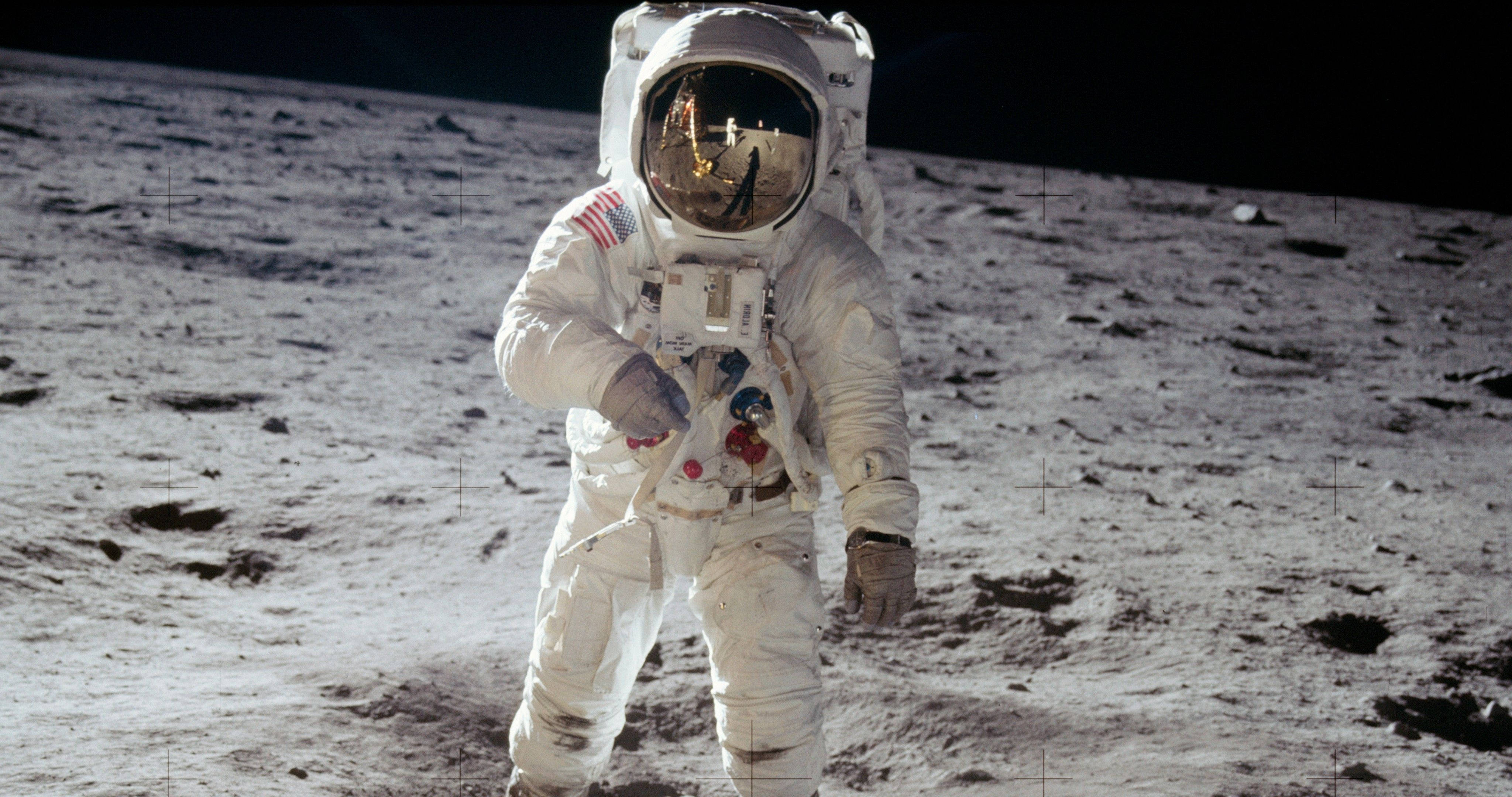 NASA 動態圖片 桌布 壁紙 — 一名穿著白色太空衣的太空人站在月球灰色的表面上，黑色天空下，頭盔反射中可見地球。