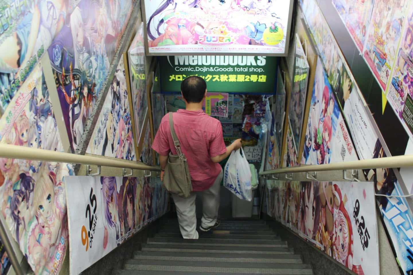 Otaku Culture 桌布 壁紙 — 一名穿著粉紅色襯衫的人沿著佈滿色彩繽紛動漫海報的樓梯往下走，通往漫畫店。