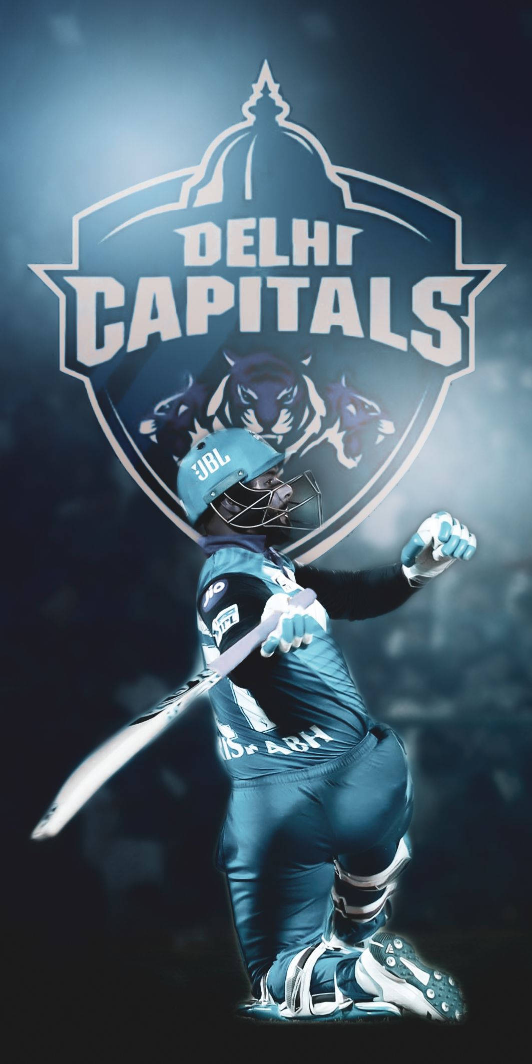 Delhi Capitals 桌布 壁紙 — 一名穿著藍色裝備的板球運動員在發光的德里首都隊標誌（帶有老虎剪影）下跪地揮拍。