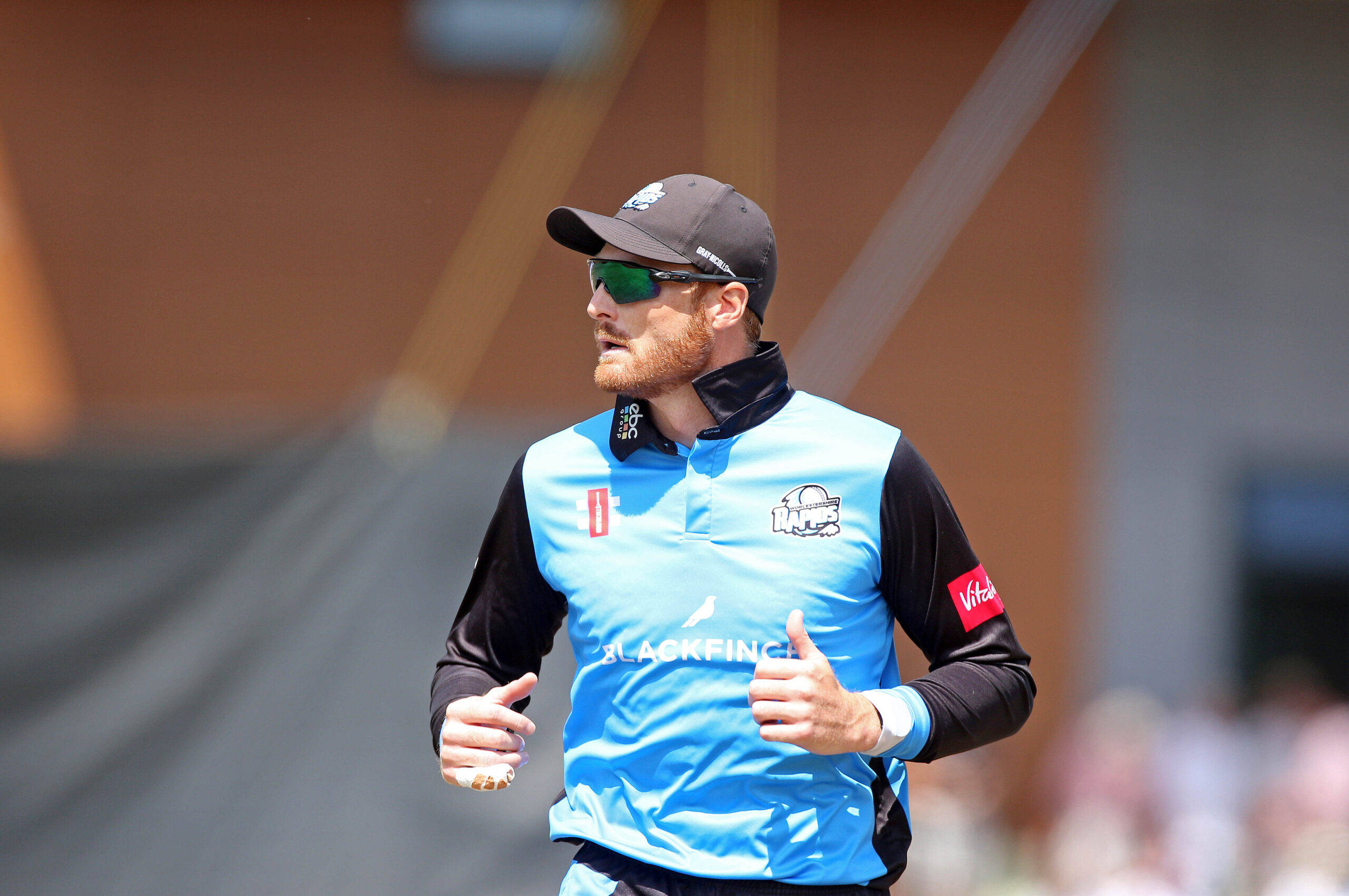 martin guptill 桌布 壁紙 — 一名穿著藍黑色球衣的板球運動員在明亮的日光下戴著太陽眼鏡和帽子，豎起大拇指。