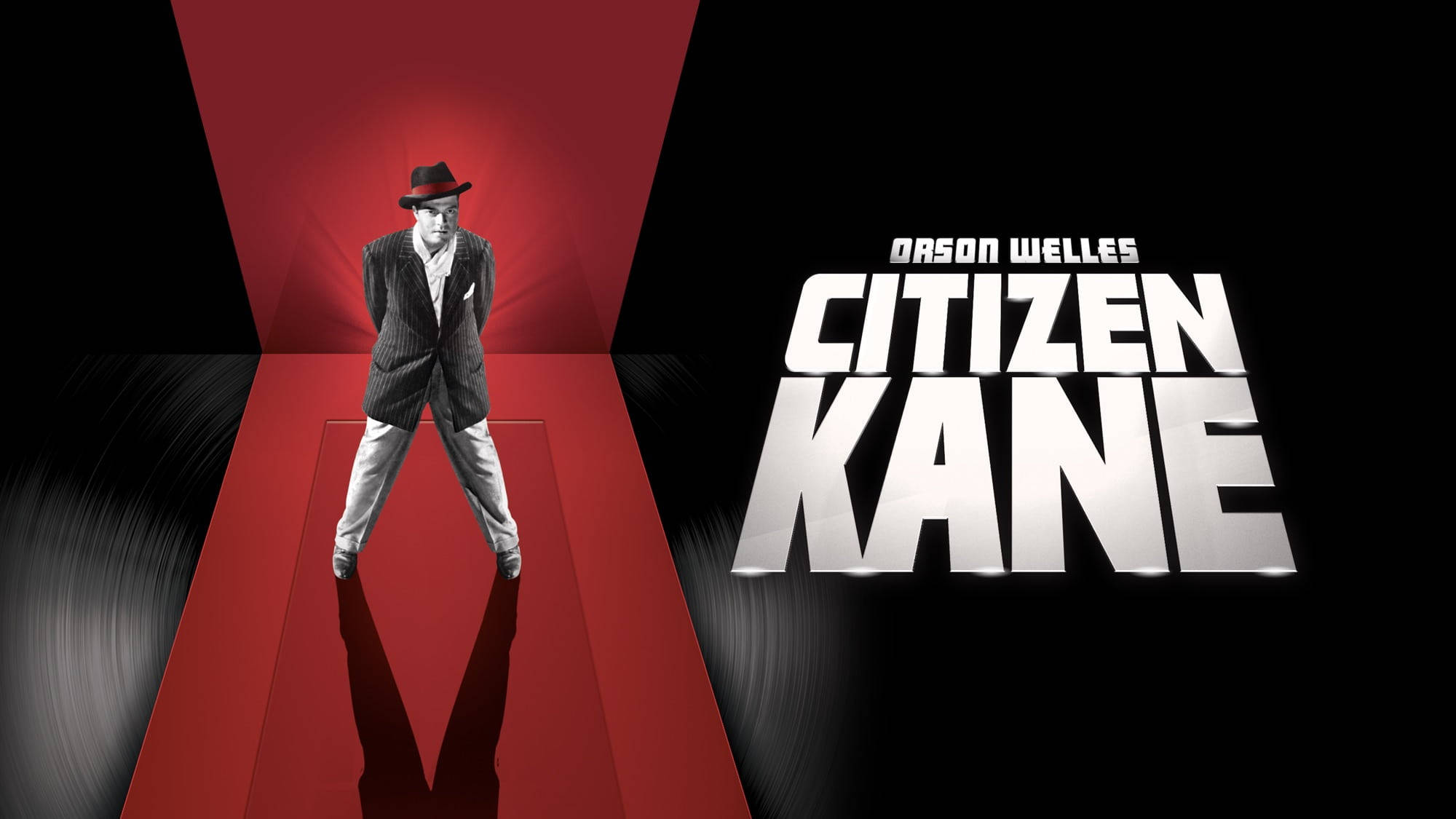 Citizen Kane 桌布 壁紙 — 一名穿著西裝和軟呢帽的男子站在紅地毯上，在戲劇性的燈光下，旁邊是粗體白色標題《大國民》。